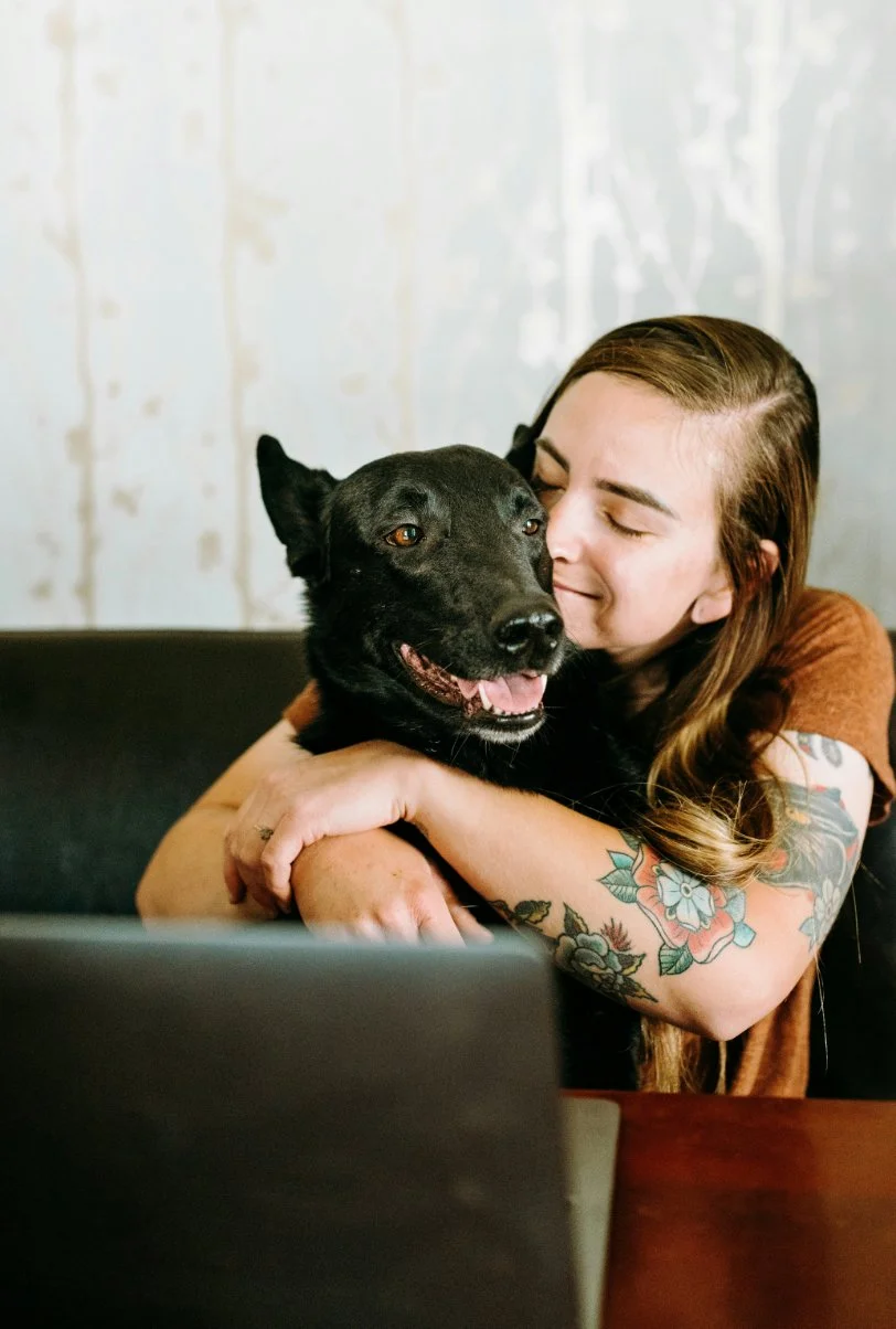 Woman hugging her dog while working at a laptop, representing comfort and connection during online therapy – EMDR therapy in Coeur d’Alene, Idaho, with intensives available in Washington and California