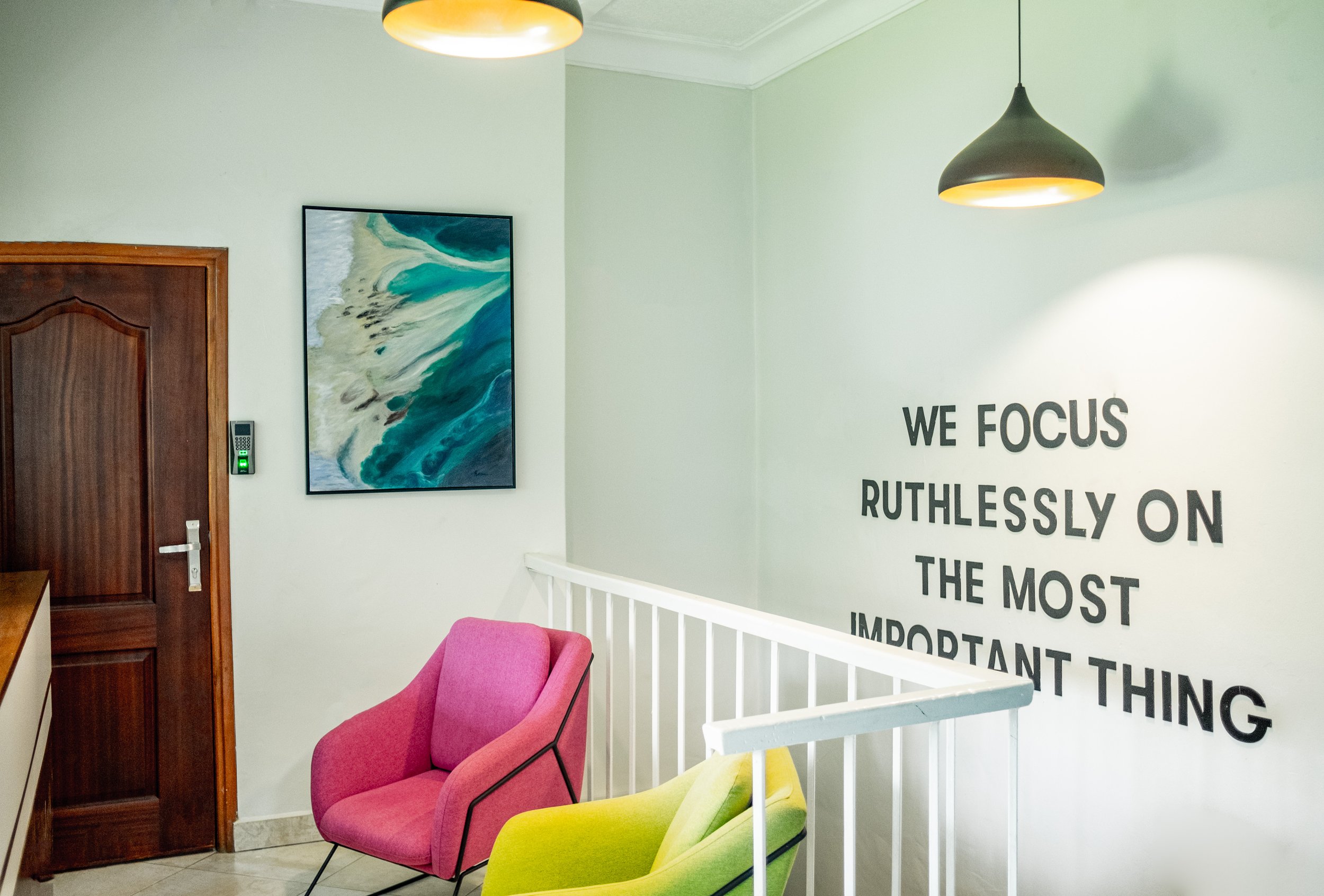 Pink and yellow accent wall chairs and blue sea wall hanging