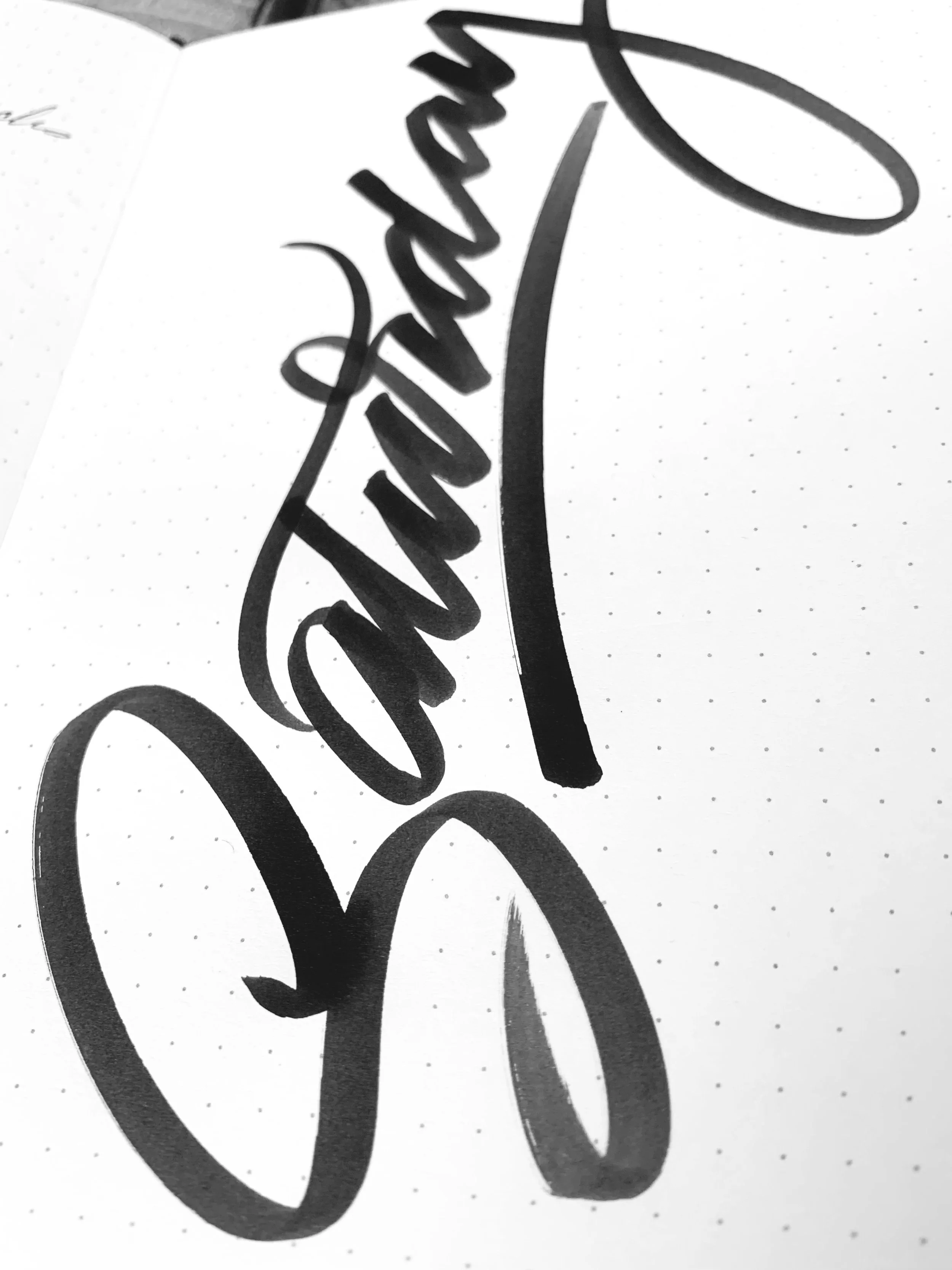 Close-up of black marker handwriting on dotted white notebook page that reads "Dreams" in a decorative cursive style.