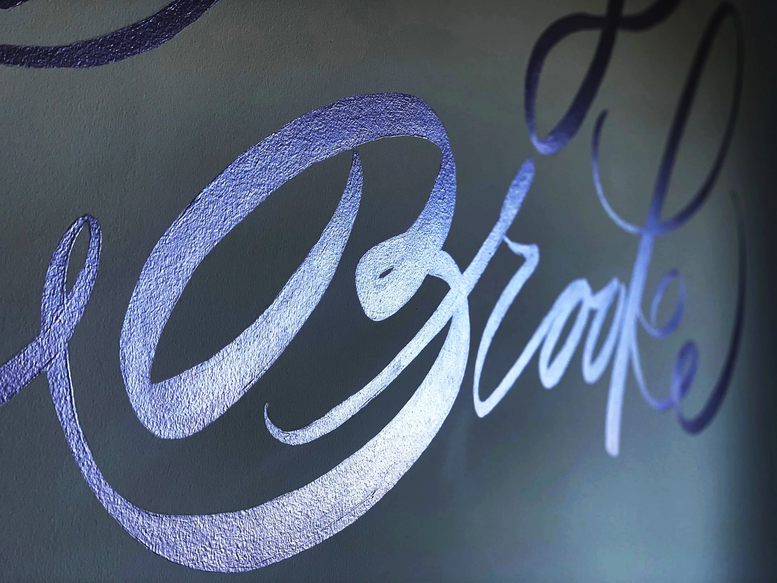 Close-up of a wall with the word "Relax" written in elegant cursive, illuminated with purple light.