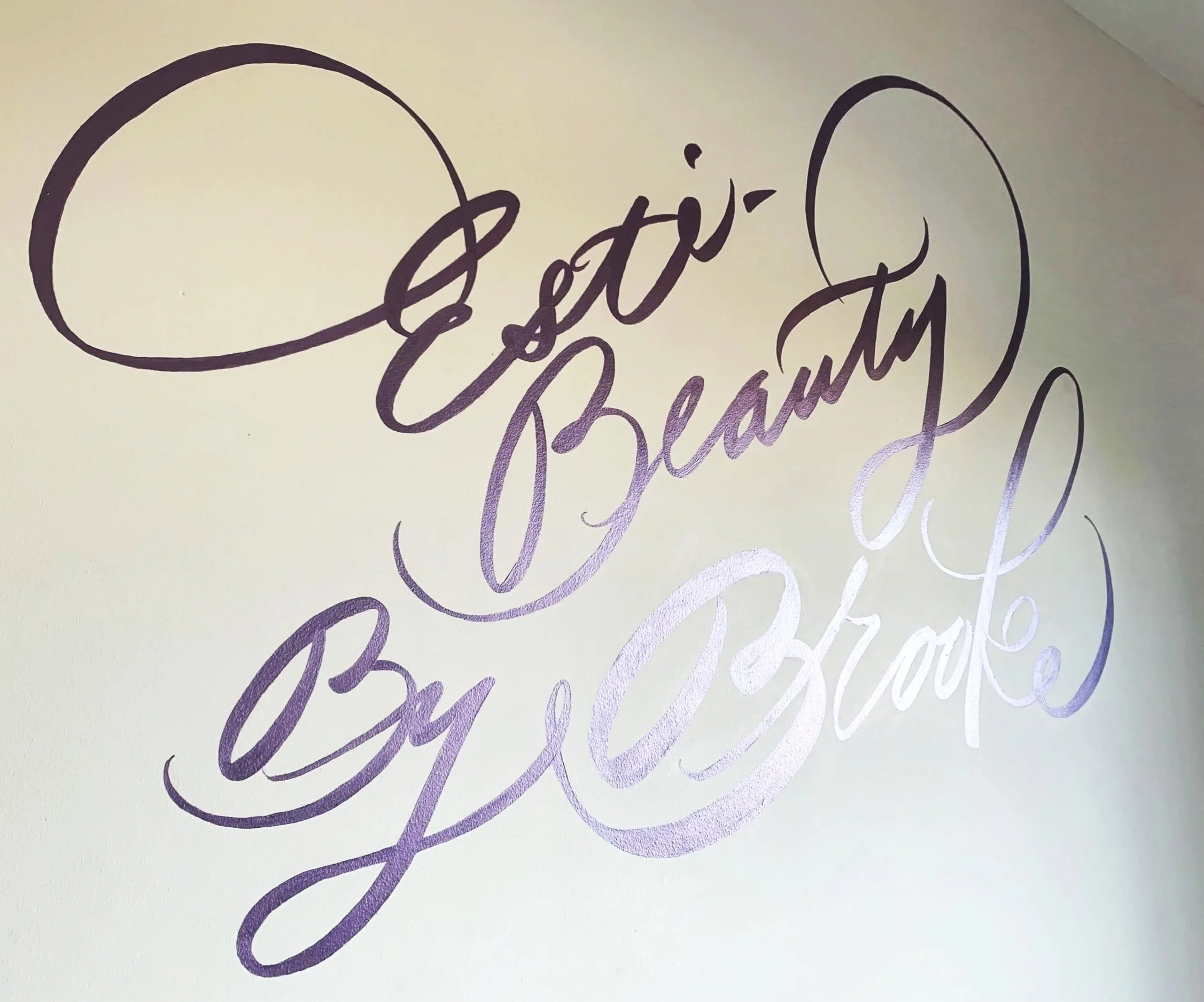 Decorative wall decal with the phrase 'Eesti Beauty by Gigi Brax' in elegant purple cursive script.