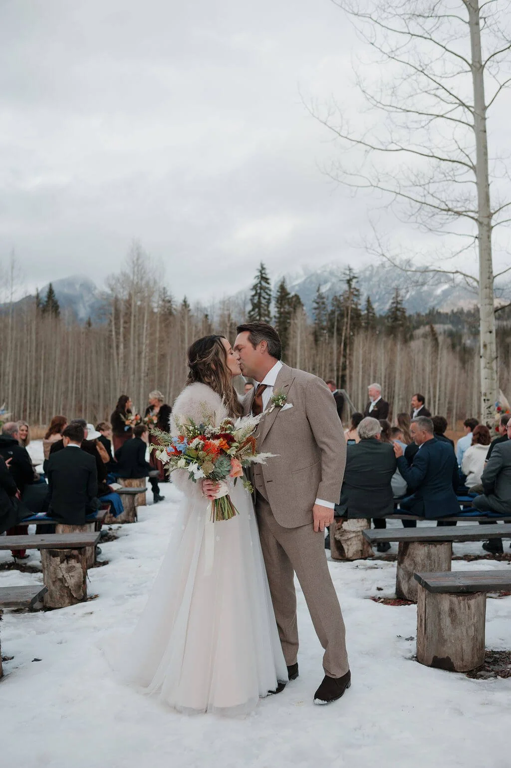 Bride poses with beautiful wedding florals in the snowy mountains of Colorado on her wedding day.