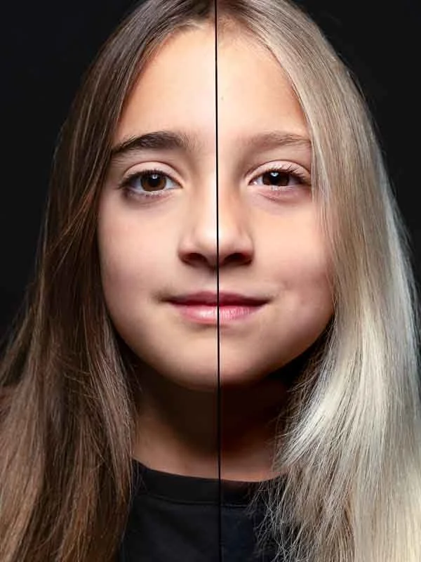 Een close-up van een jong meisje met lang bruin haar aan de linkerzijde en lang blond haar aan de rechterzijde, tegen een zwarte achtergrond.