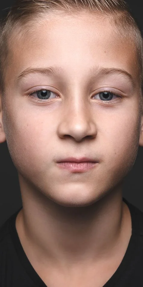 Kinderportret van jongen in fotostudio in Zoetermeer met rustige blik en donkere achtergrond