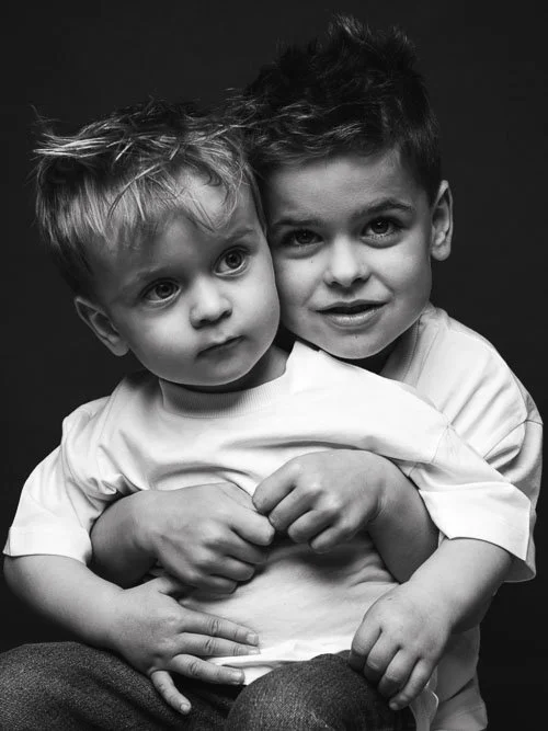Twee broertjes dicht tegen elkaar tijdens een speelse fotoshoot