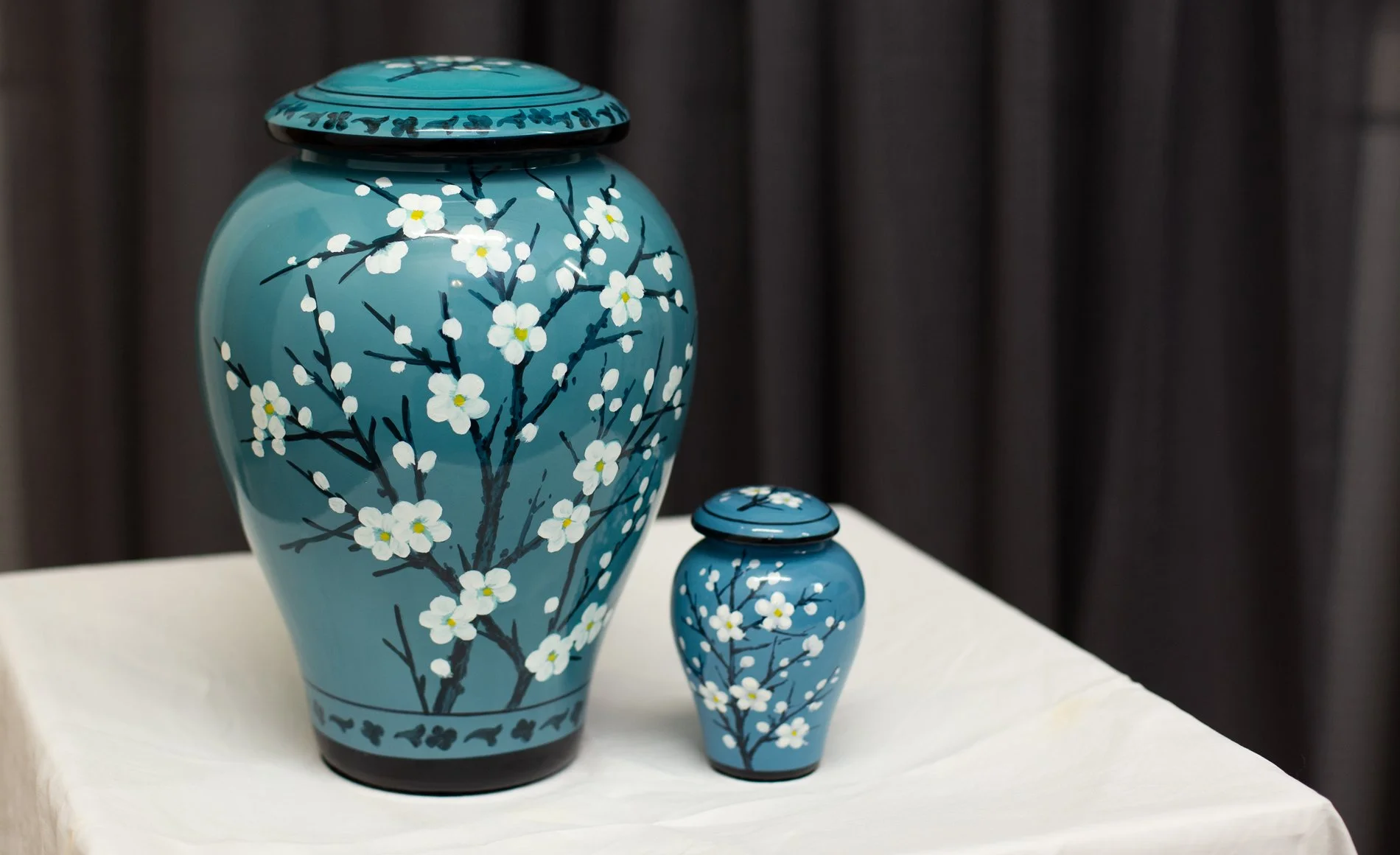 Two blue ceramic vases with white floral and branch designs on a white surface.