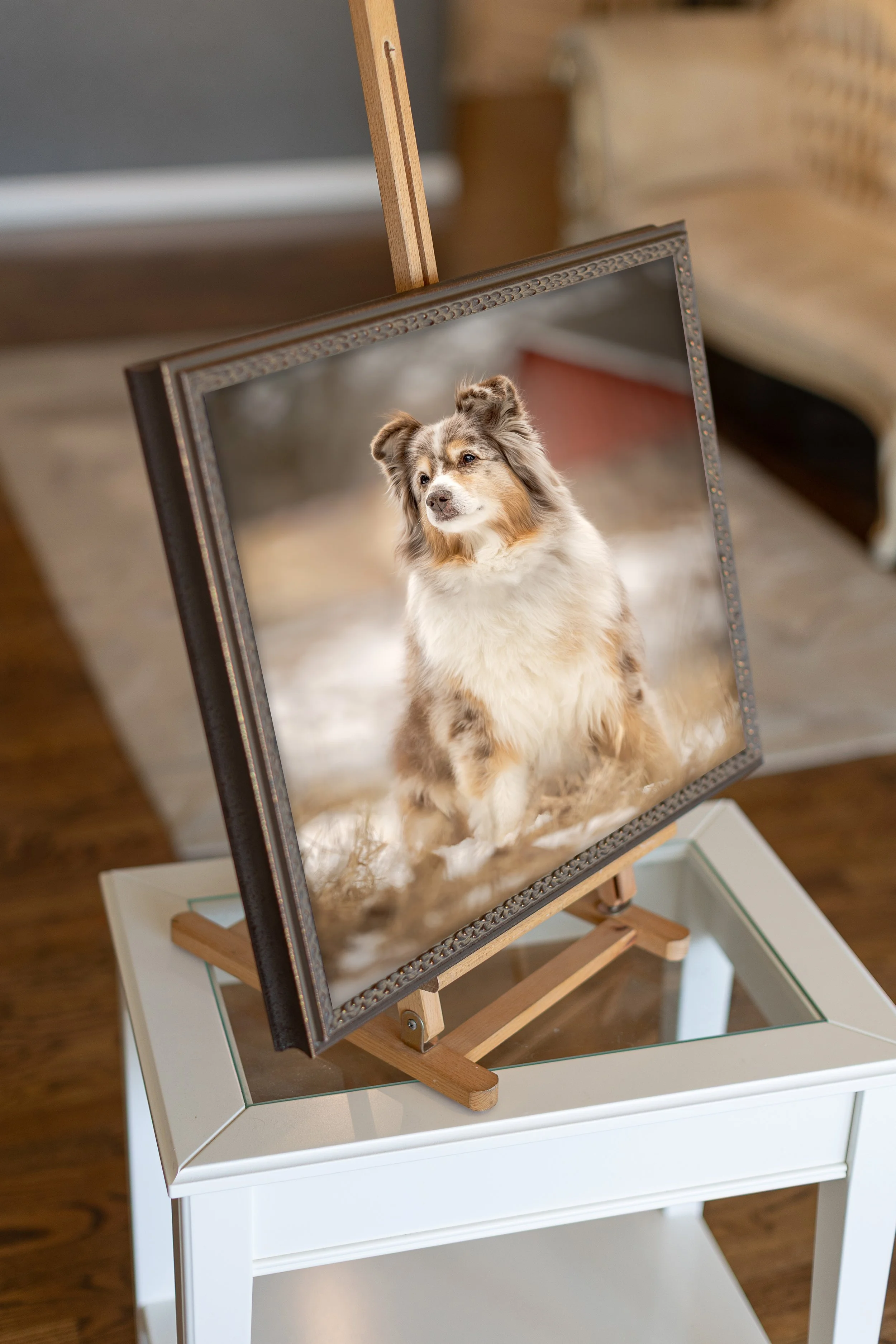 A framed photograph of a dog on an easel, placed on a white table.
