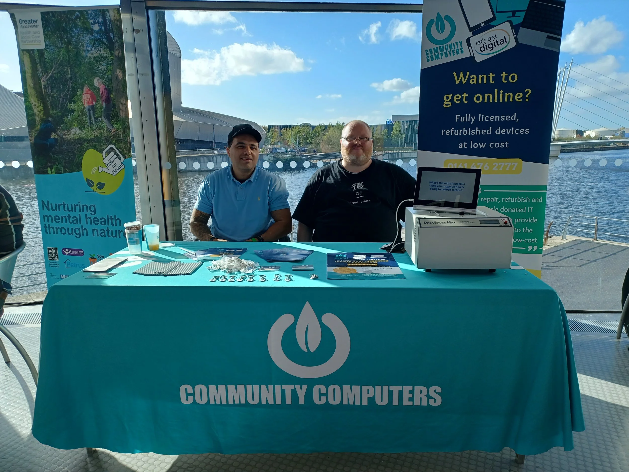 2 people sat at  a table with Community Computers Logo