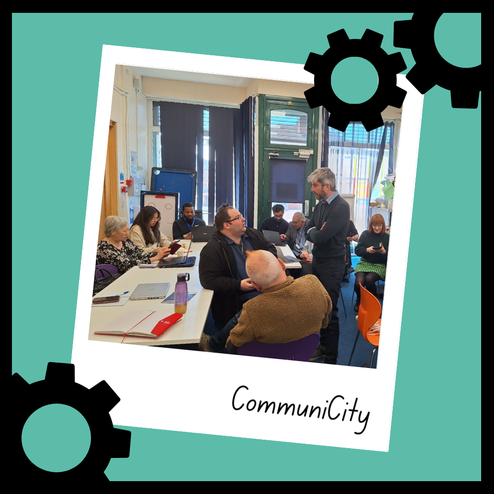 A snapshot from Manchester City Council's CommuniCity project. Members of VCSEs and community organisations try out a tech-enabled tool on their laptops. The developer of the app is pictured, deep in conversation.