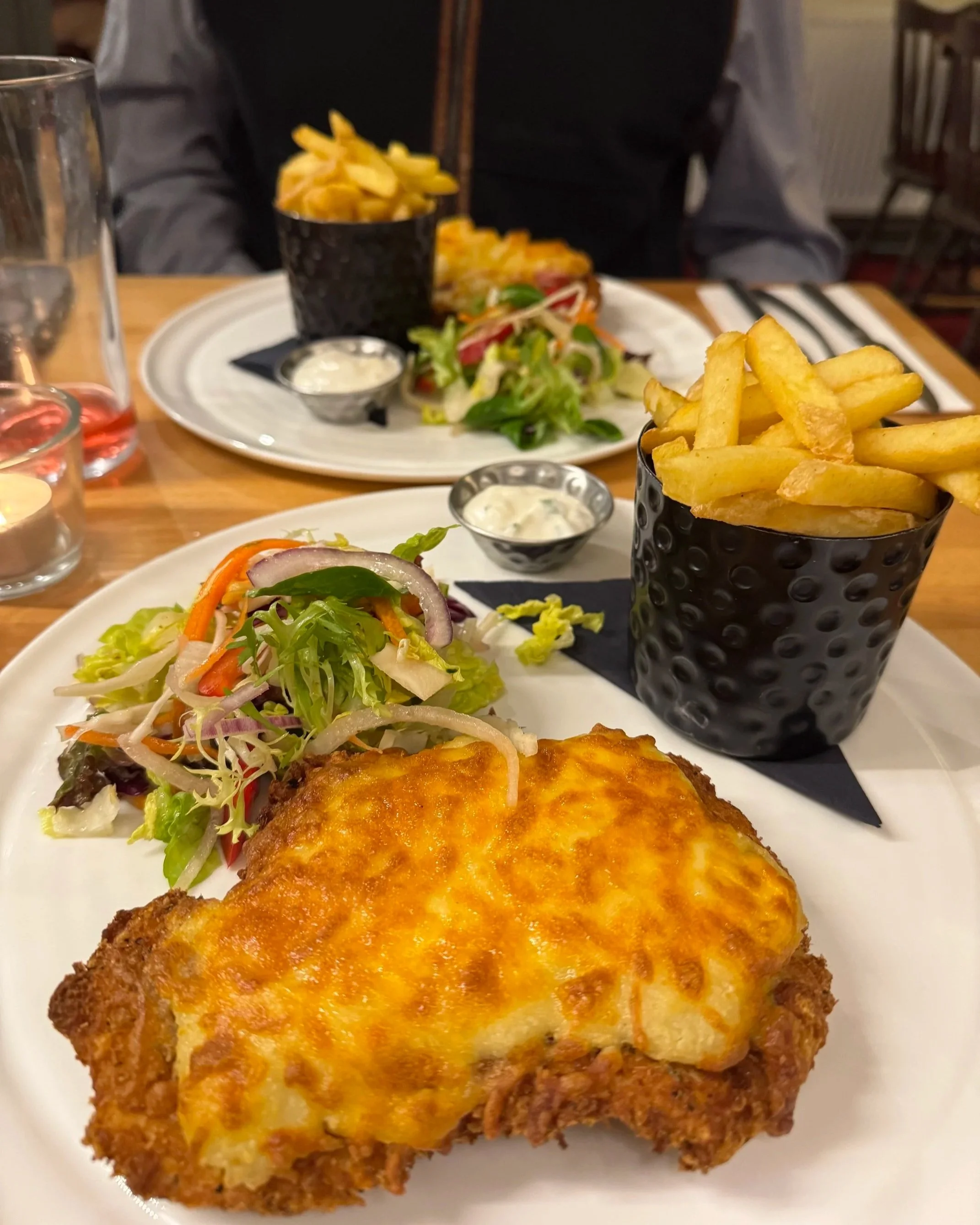 Chicken parmo on a plate with salad and fries