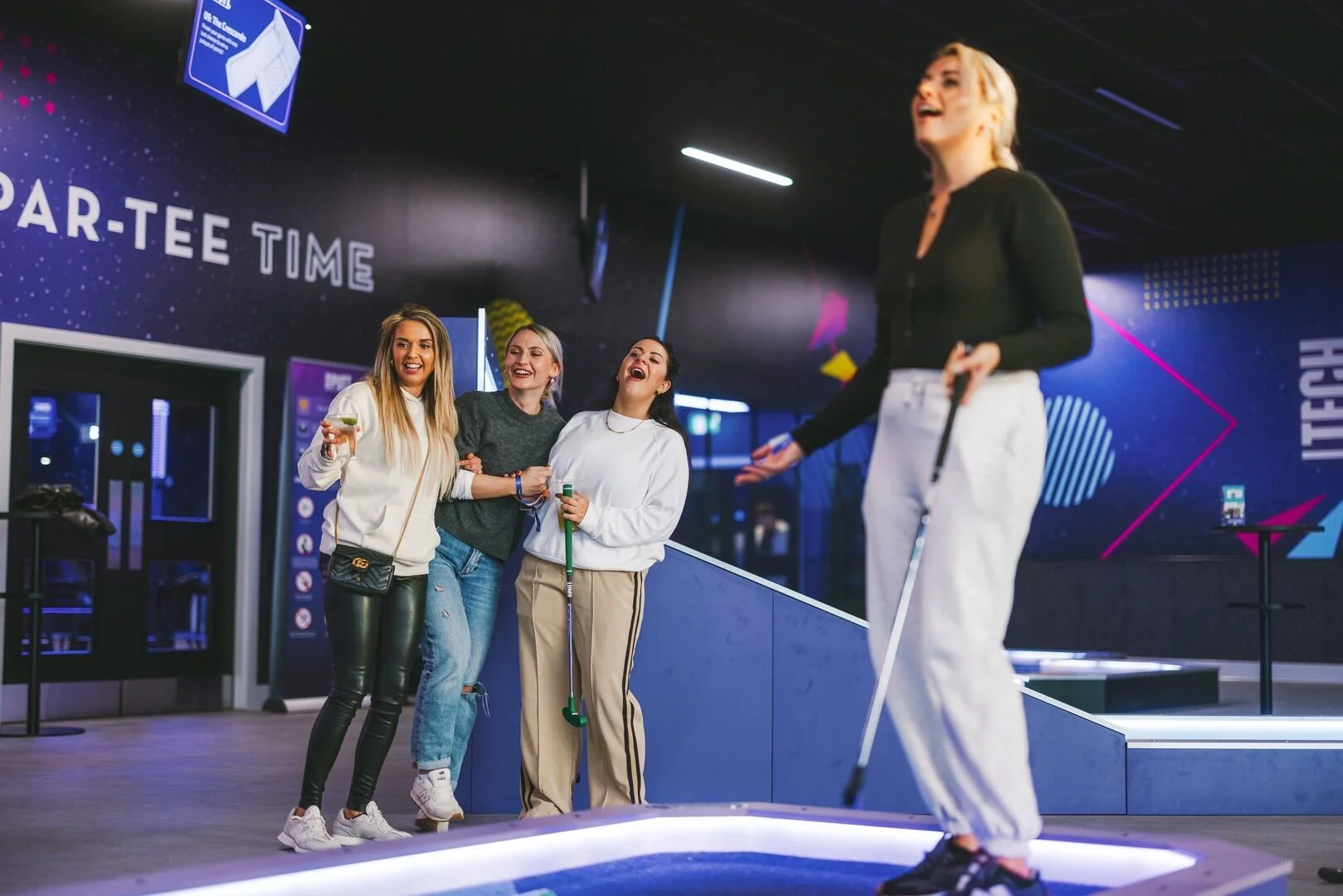 Group playing 360Golf interactive mini golf at an indoor entertainment venue.