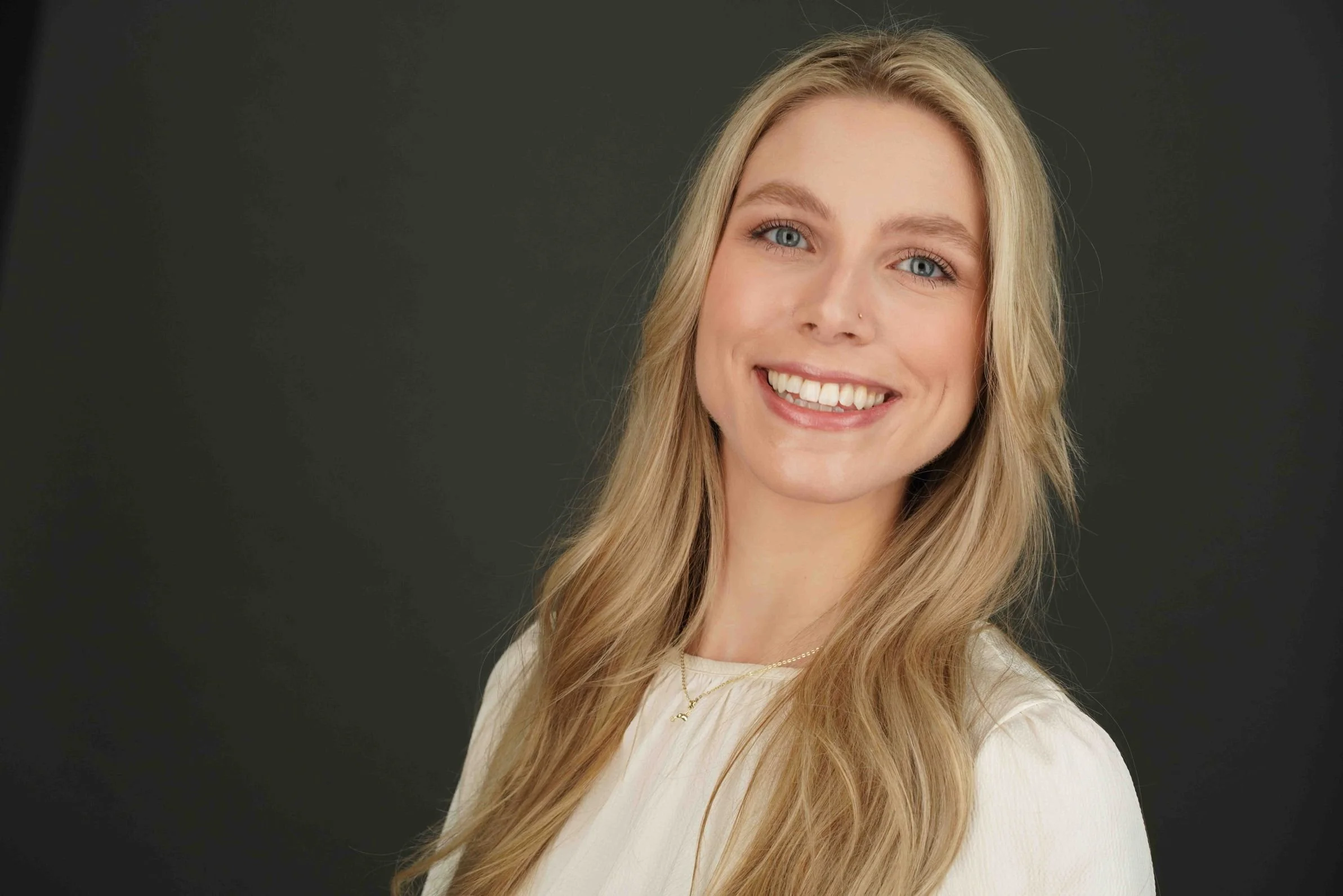 Headshot of a blonde white woman wearing a white shirt and smiling