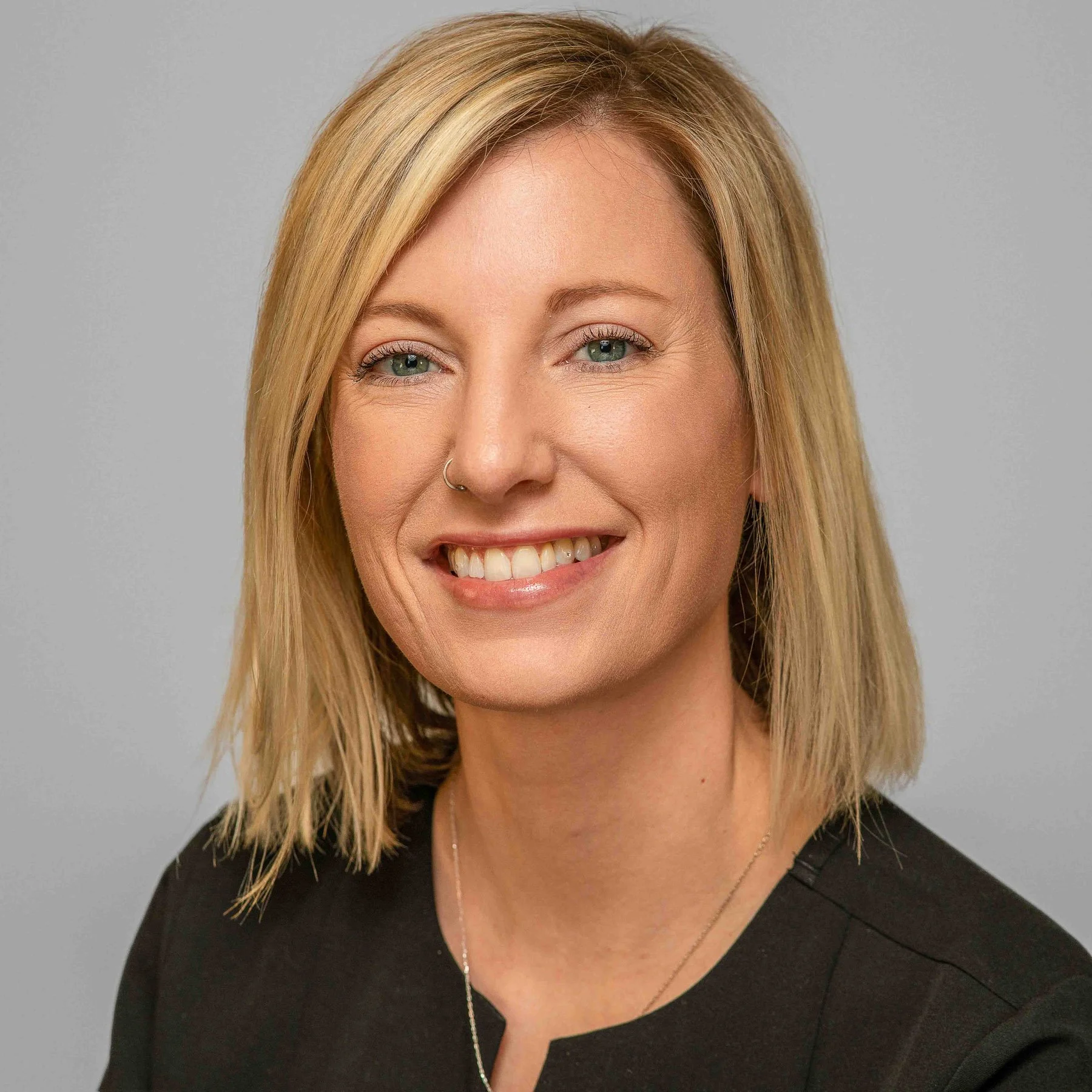 Headshot of a middle aged blond woman smiling and wearing a black blouse.