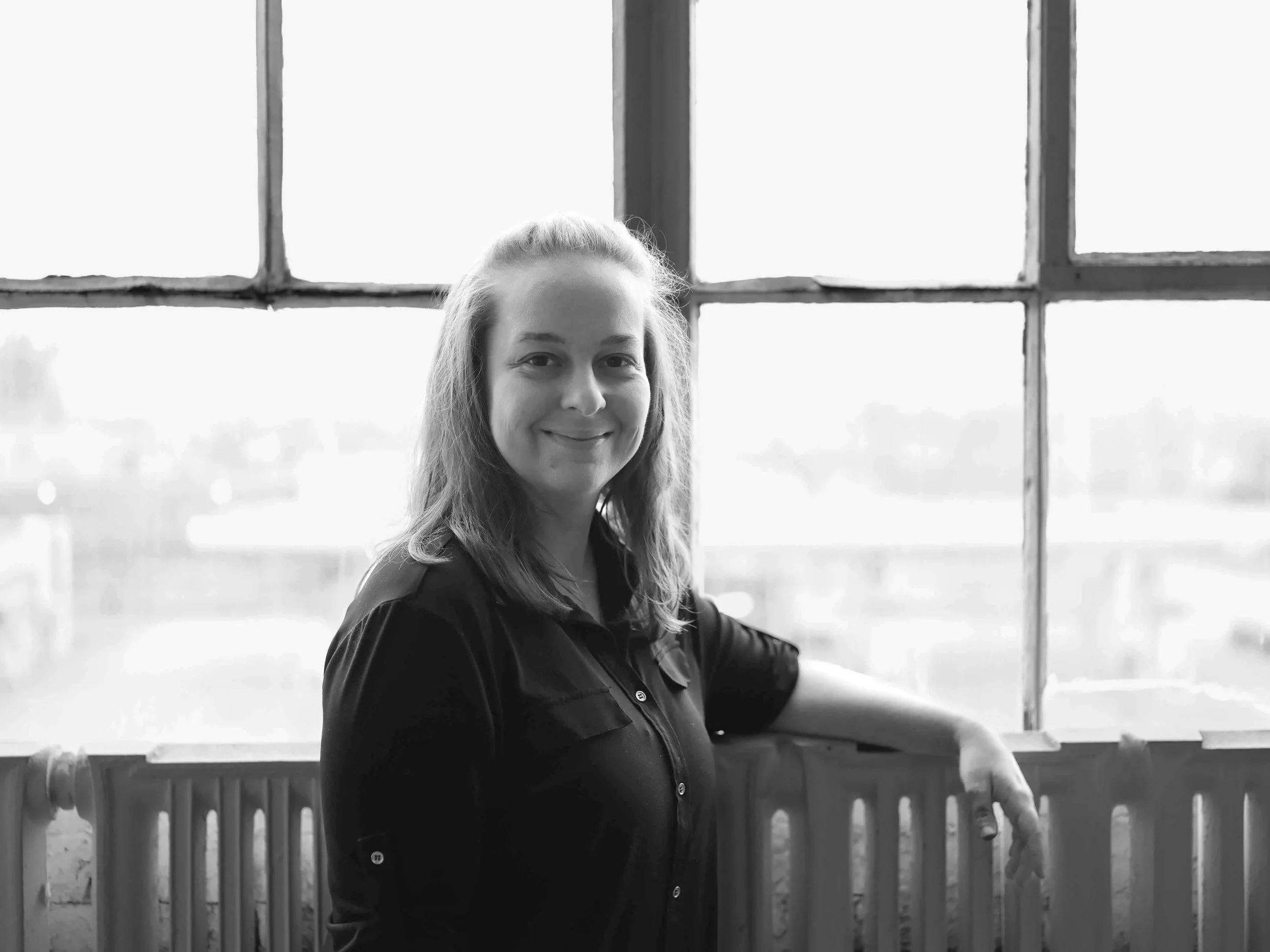 Black and white personal branding style headshot of a young woman wearing a black button up blouse and smiling