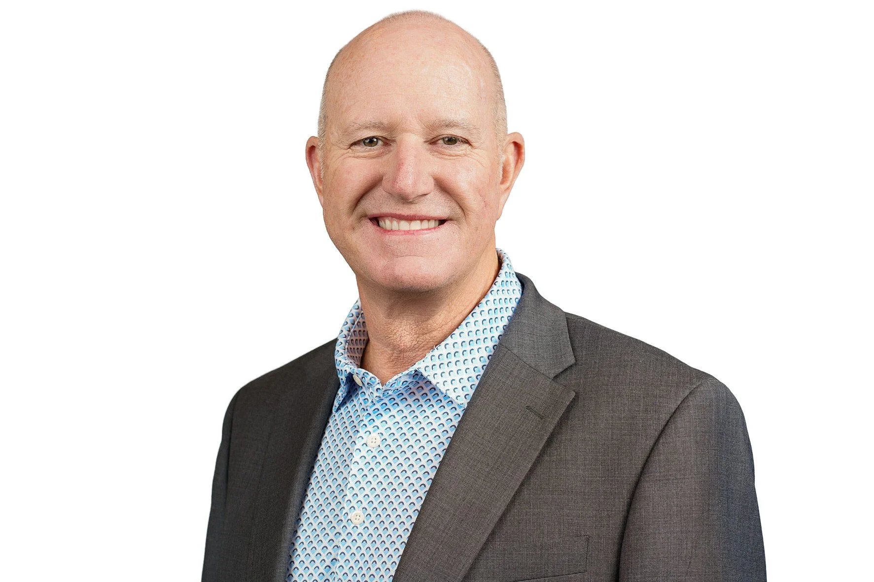 Headshot of a bald man with a blue button down and grey overcoat.