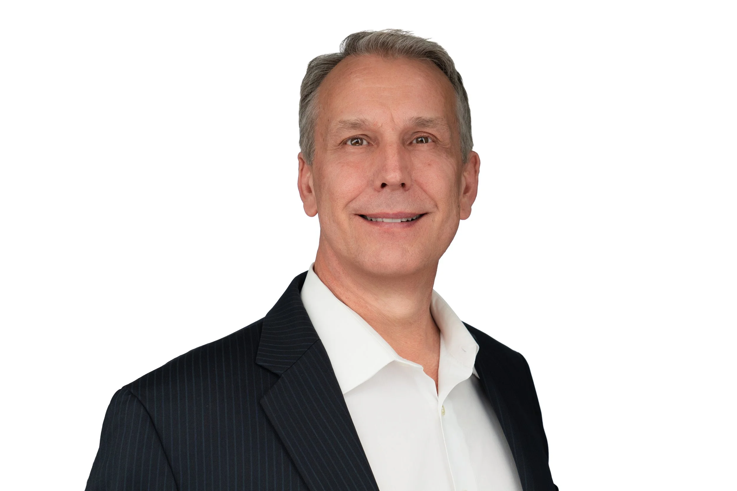 Headshot of a white man with short hair wearing a white button up and black blazer in front of a white background