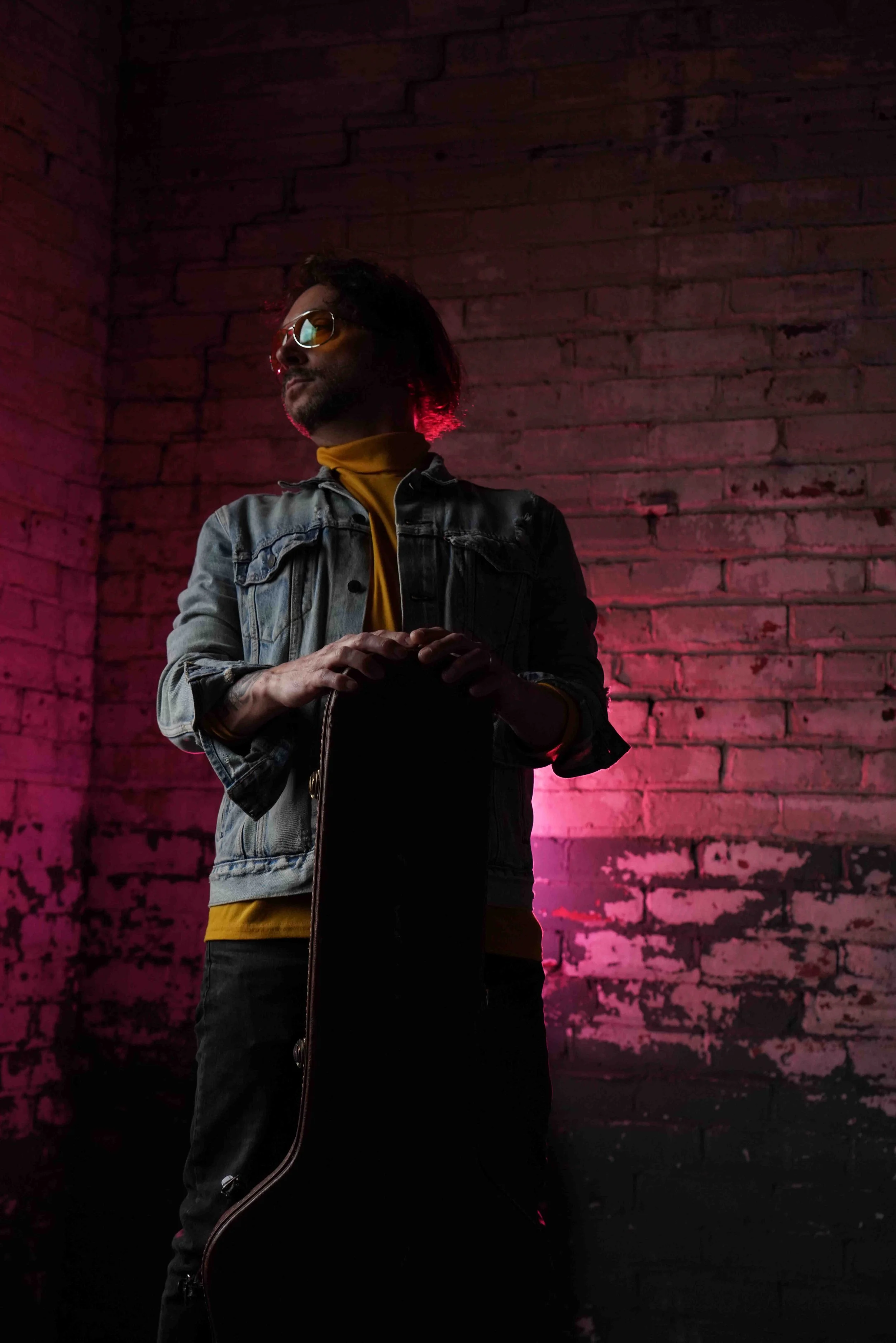 Portrait style headshot of a musician in dim red lighting