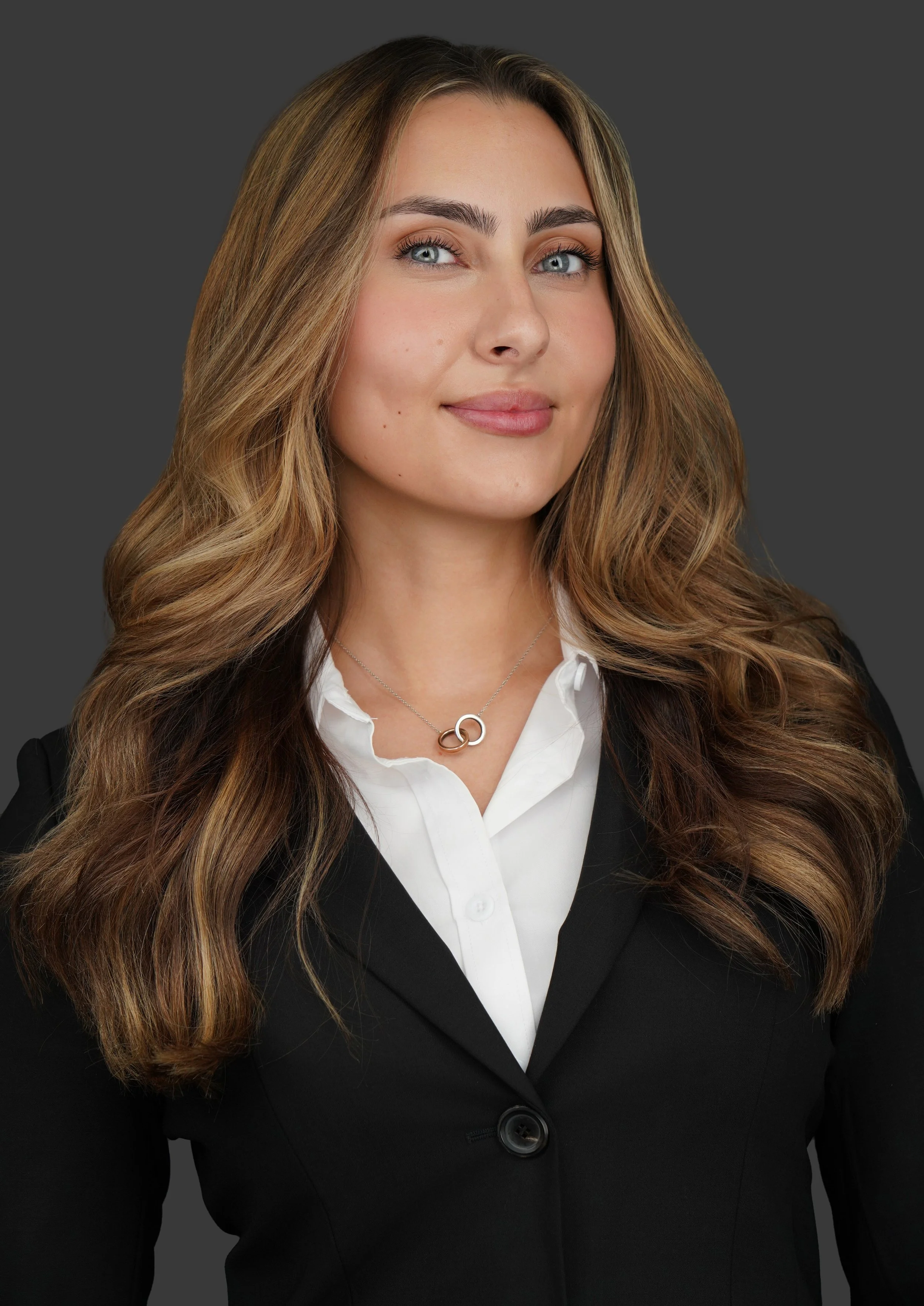 Headshot of a young woman with long hair wearing a black blazer over a white button up