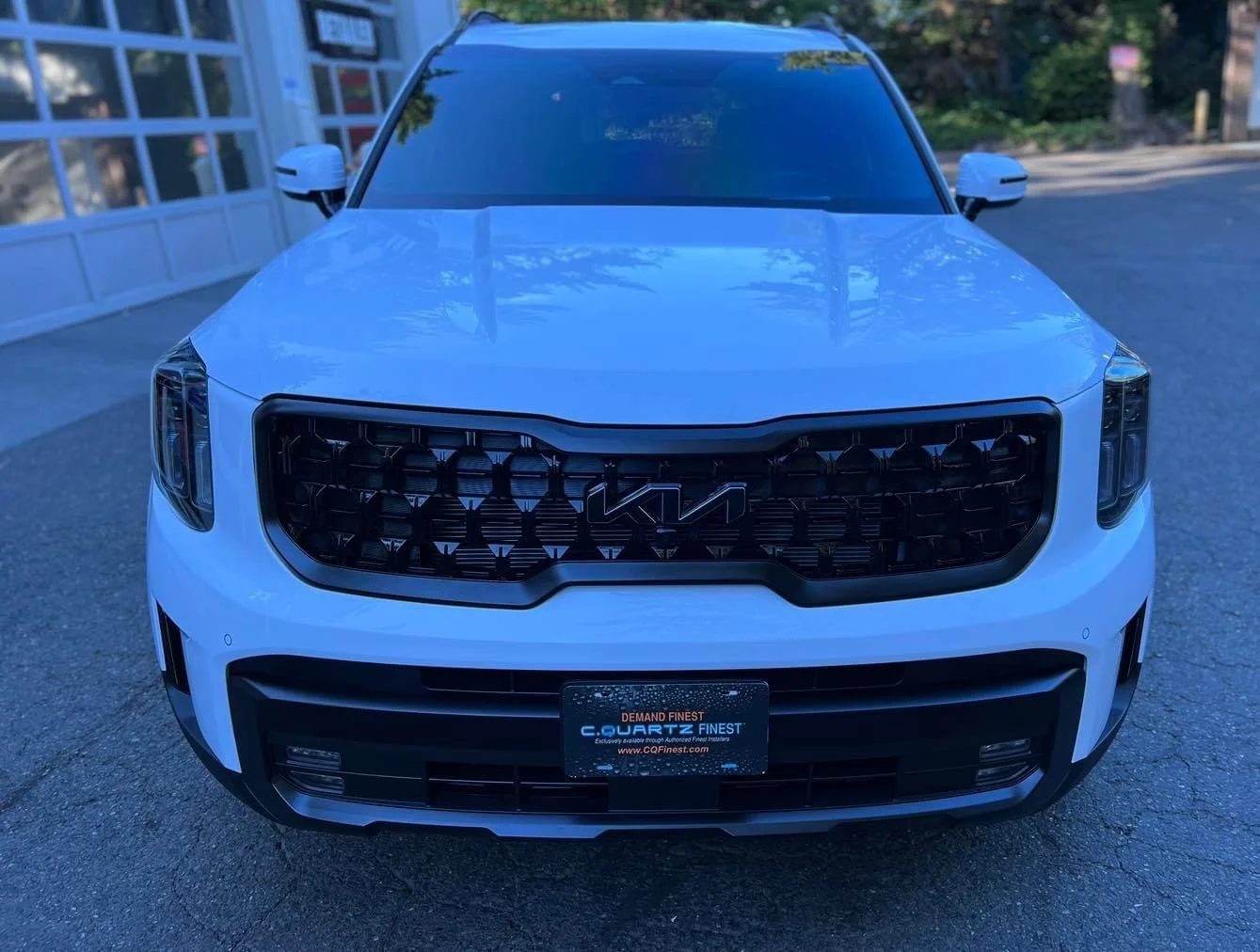 Front view of a white Kia SUV parked outdoors.
