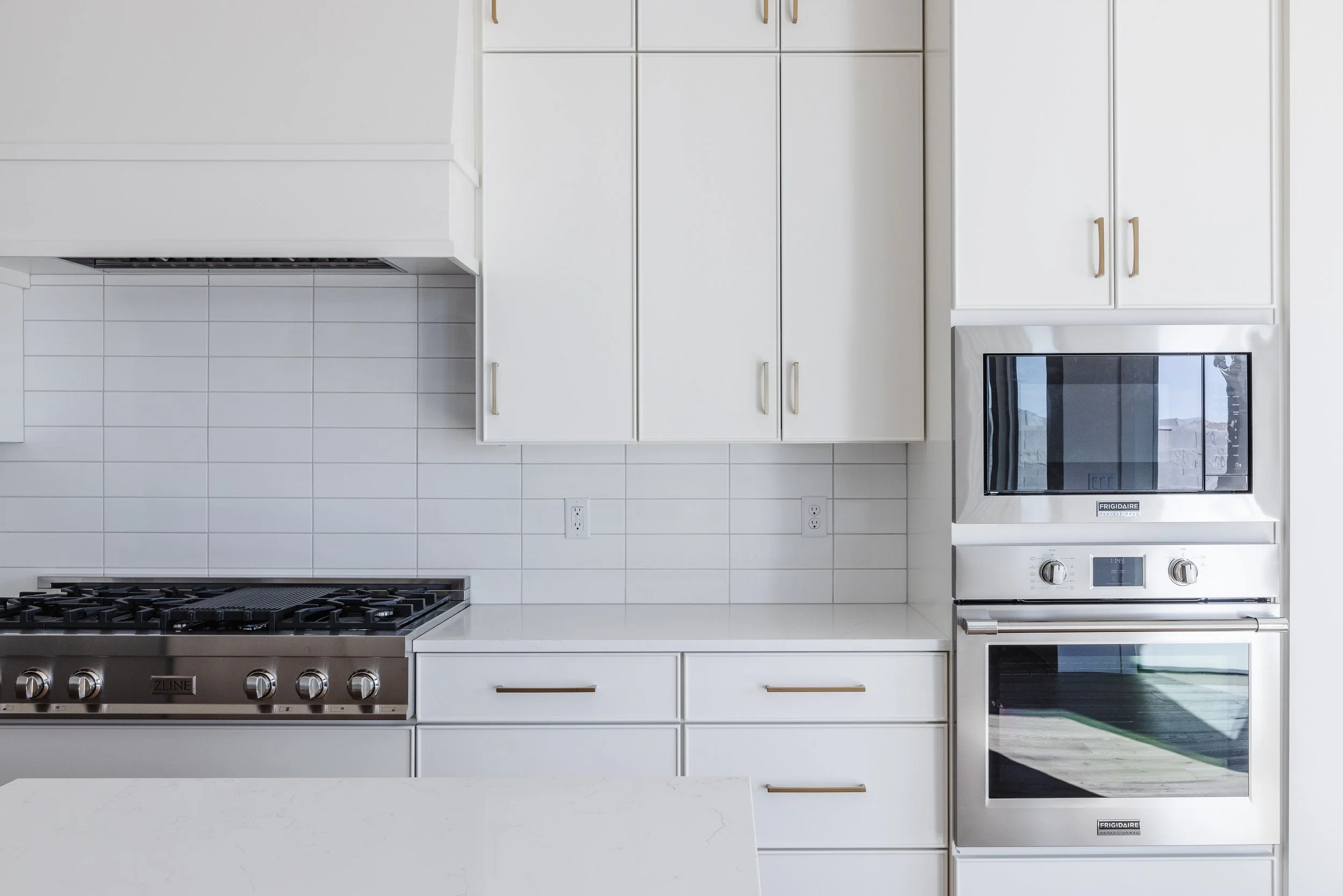 Modern white kitchen with stove, oven, microwave, and cabinets.