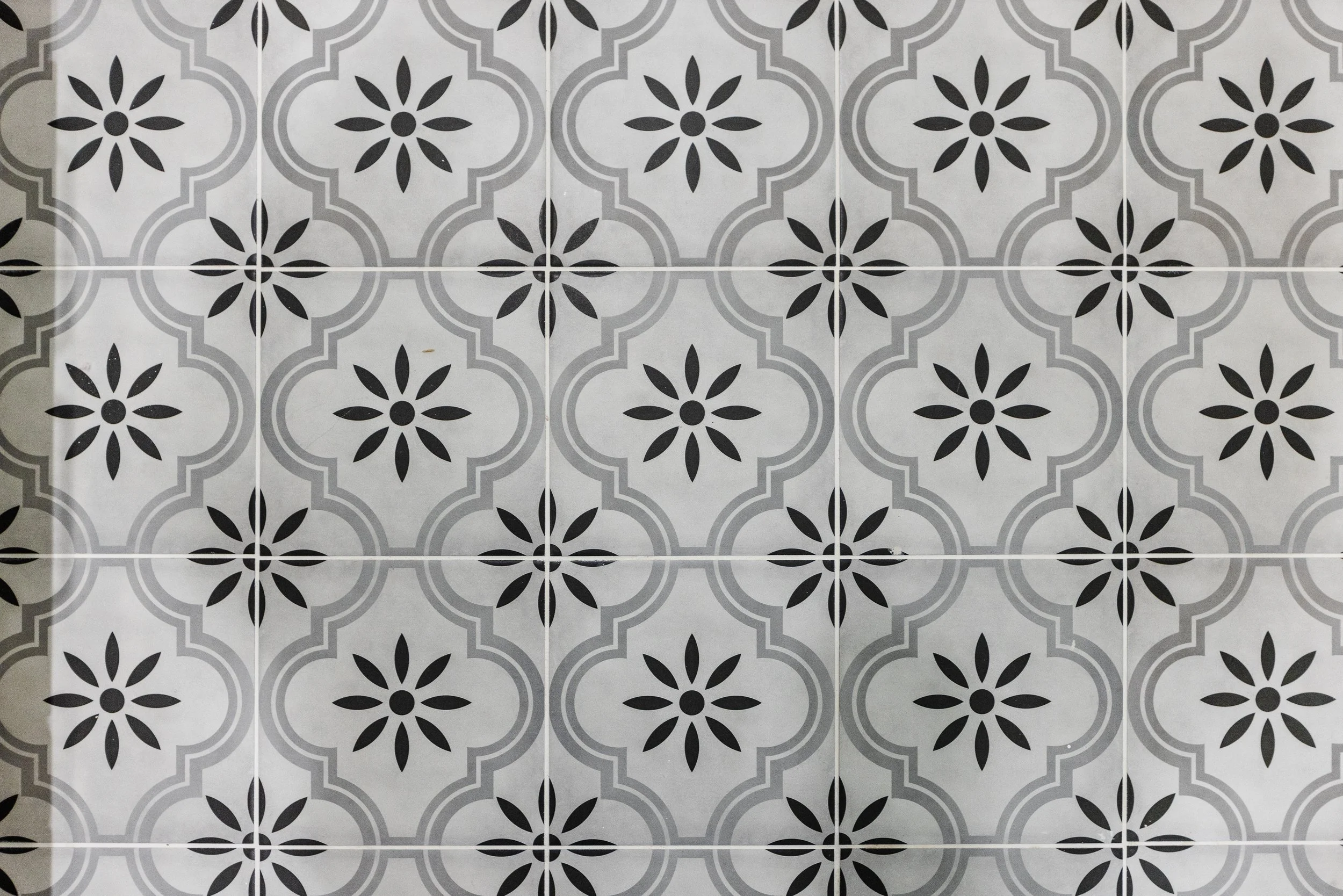 Patterned black and white tiles with geometric and floral designs arranged in a grid.