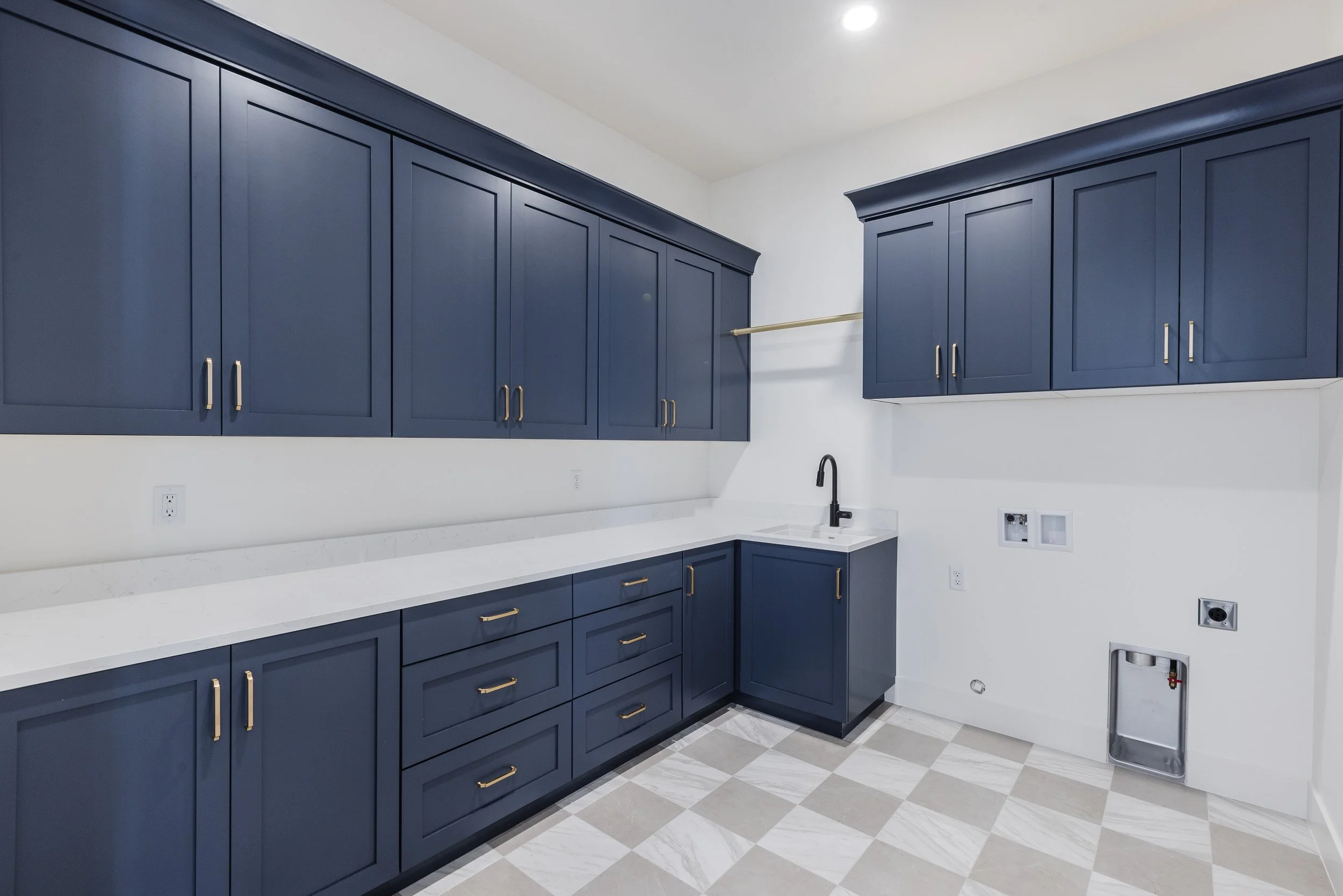 Kitchen with blue cabinets, white countertops, a black faucet, and a floor with gray and white checkerboard tile pattern.