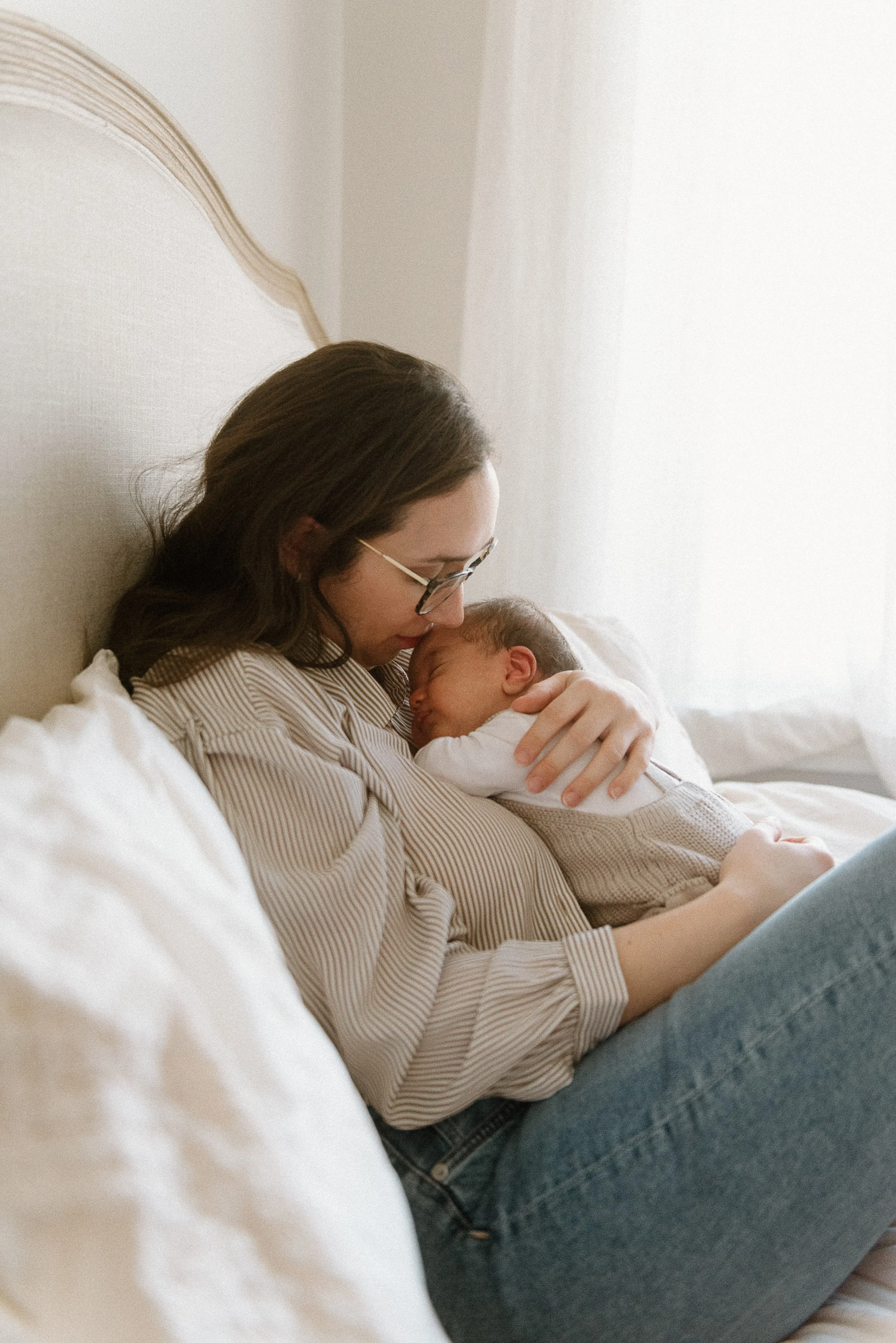 Mother holding sleeping newborn while sitting up.