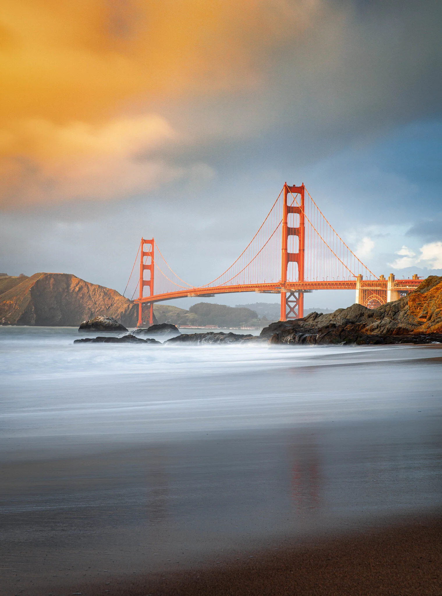 Golden Gate Bridge at sunset with sandy beach in foreground, San Francisco, California.