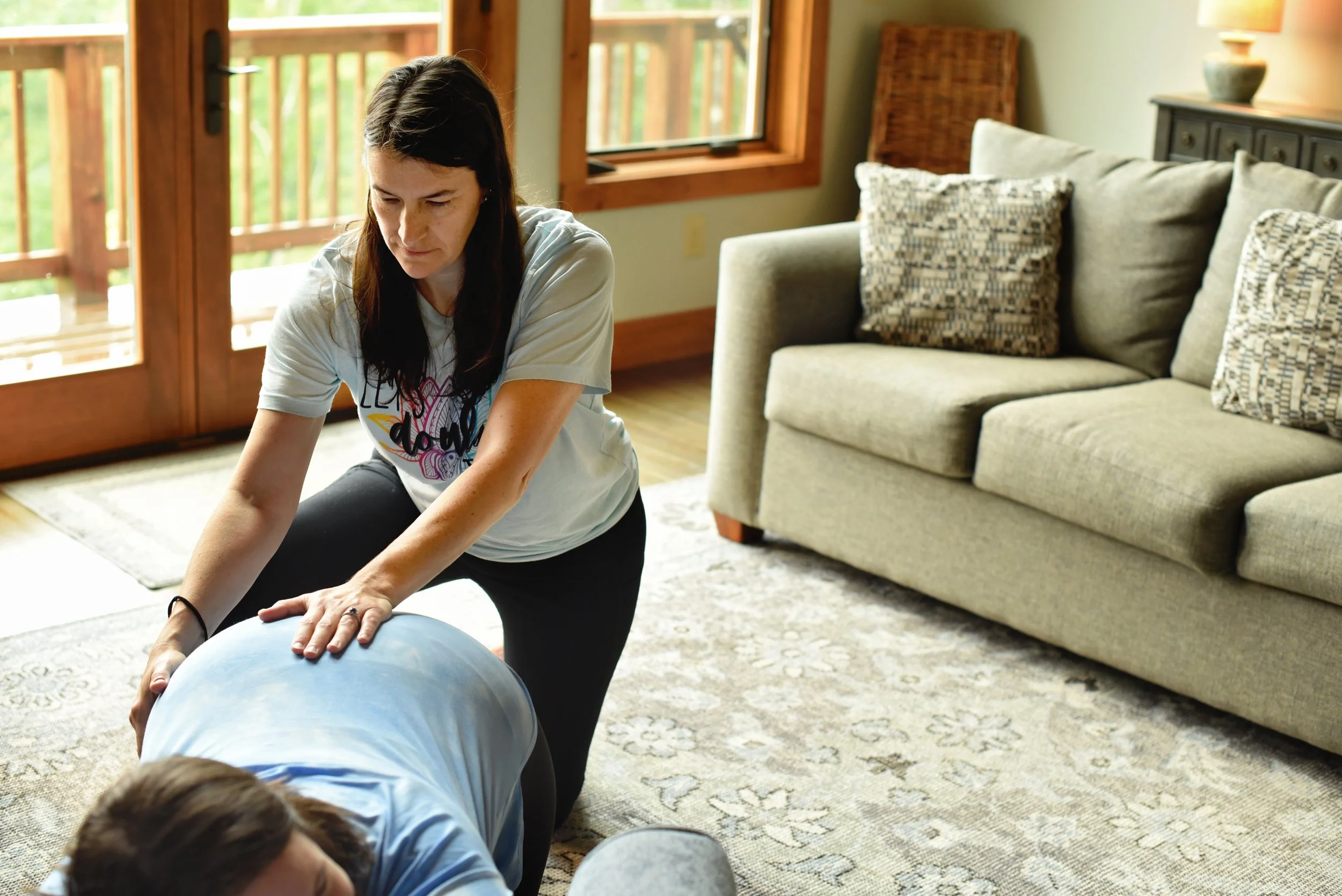 Abby Steffen providing doula services to a woman in labor lying face down on the floor.