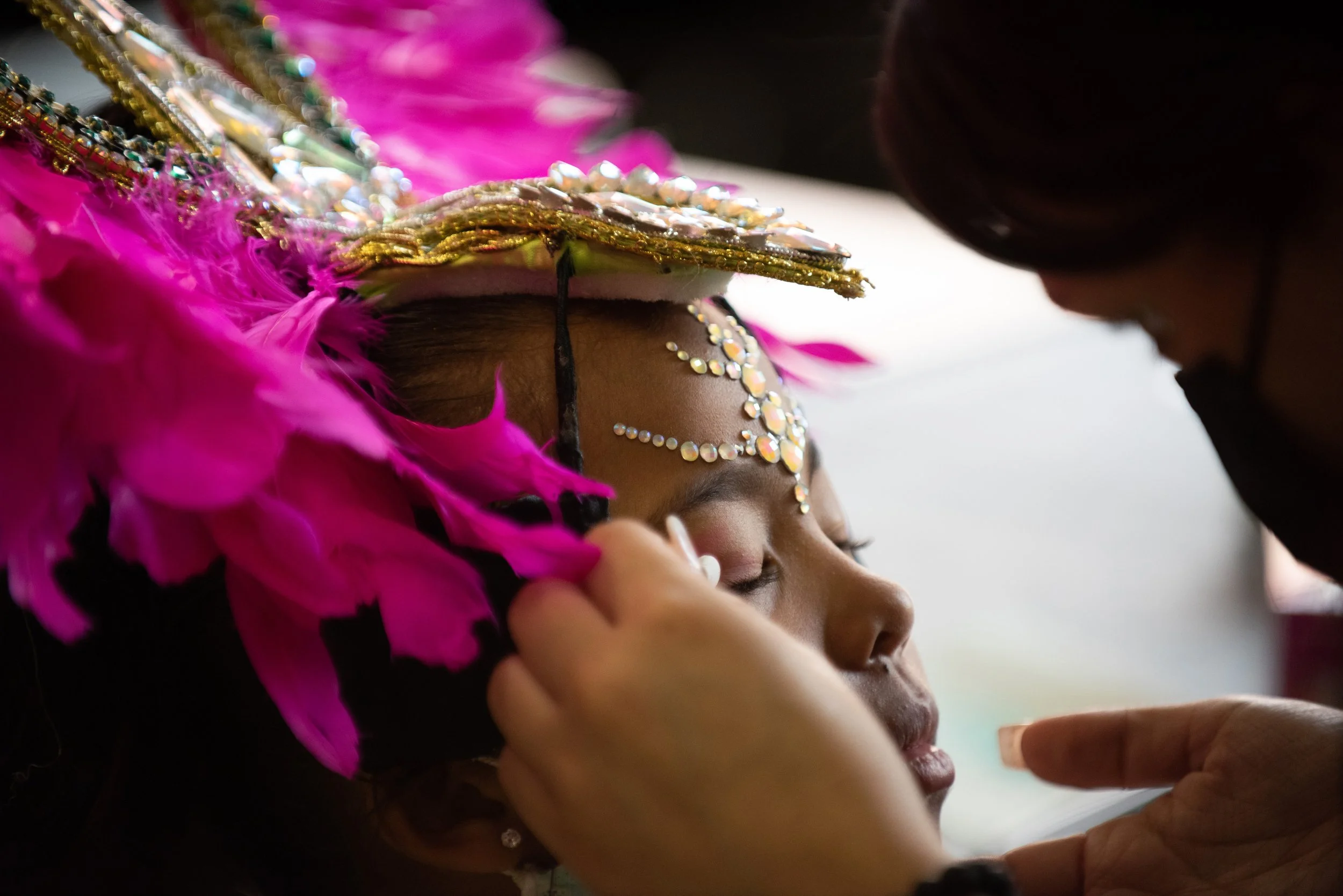 A child performer with the Grupo Cultural Latinos en Rochester has her eye makeup done after getting into costume and having fake jewels applied to her forehead, at the Kodak Center in Rochester, New York on October 2, 2021. 