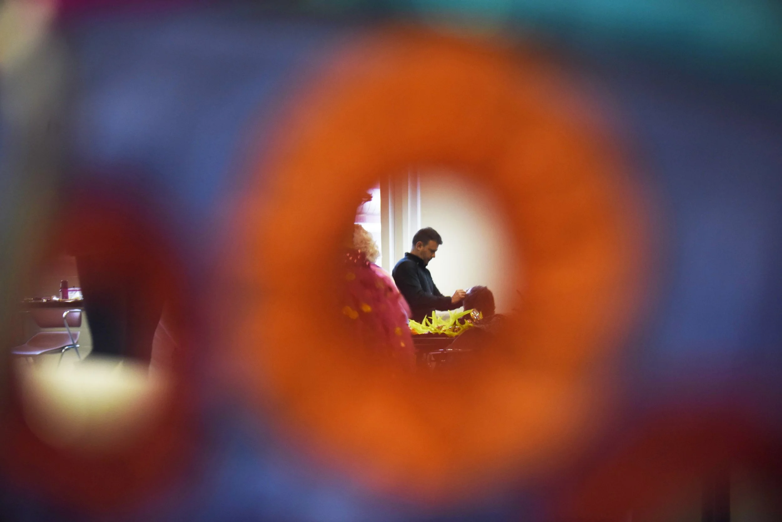 A headdress artist sews fake fur to a collar before the show