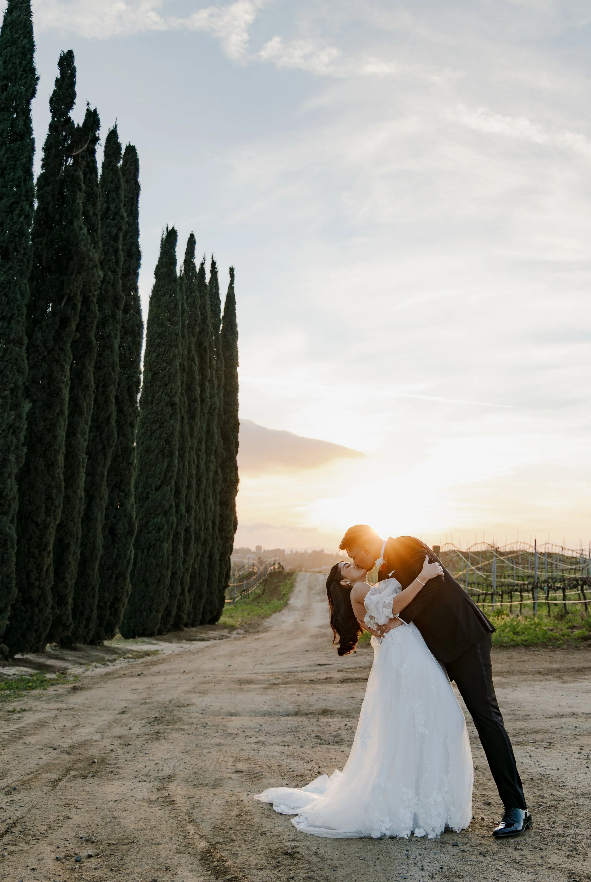 A bride and groom kiss during sunset at Danza Del Sol Winery in Temecula, California. Photographed by Drew Ramsey Photography, a Southern California Wedding Photographer.