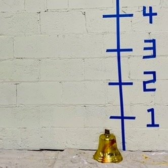 gold bell against white wall with dimensions
