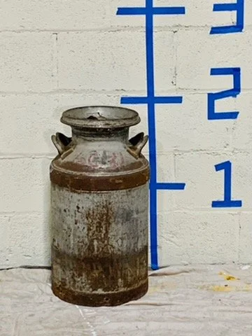 rustic milk can against white wall