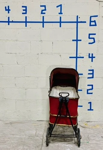 front view vintage red pram against white wall with dimensions