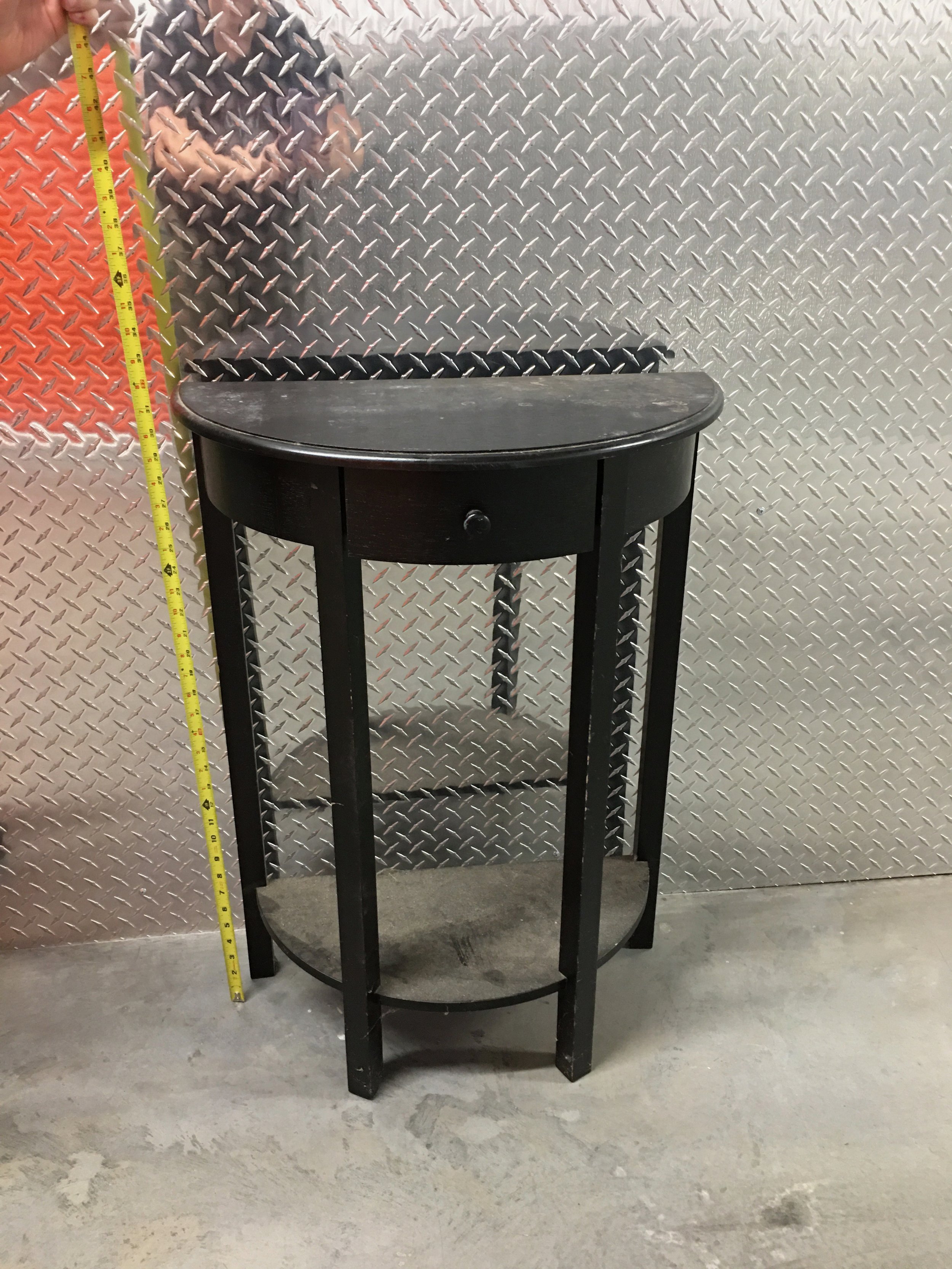 black wood half table against metal wall with tape measure