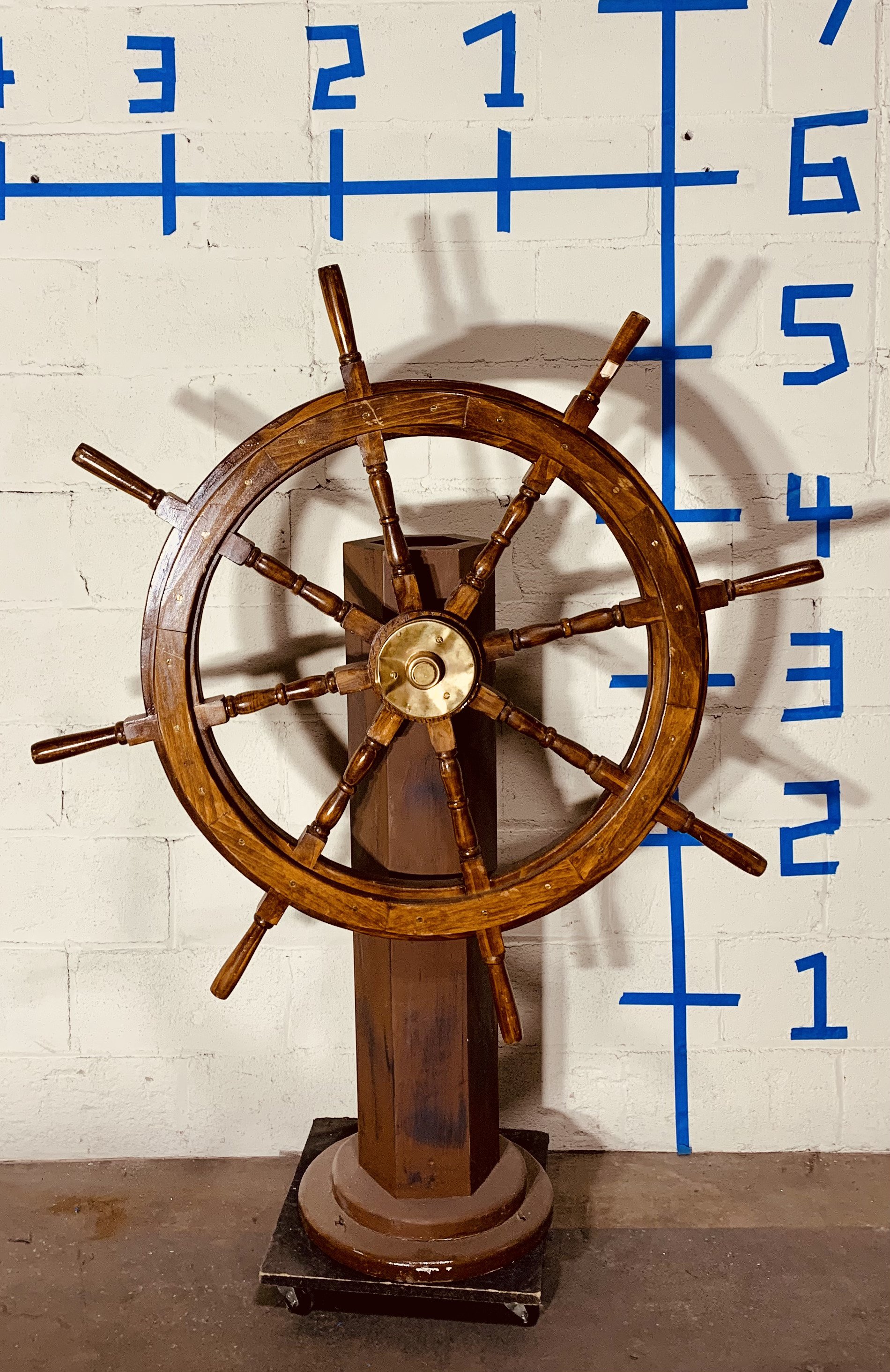 Wood captain’s wheel against white wall with dimensions