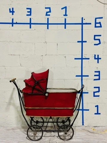 side view vintage red pram against white wall with dimensions