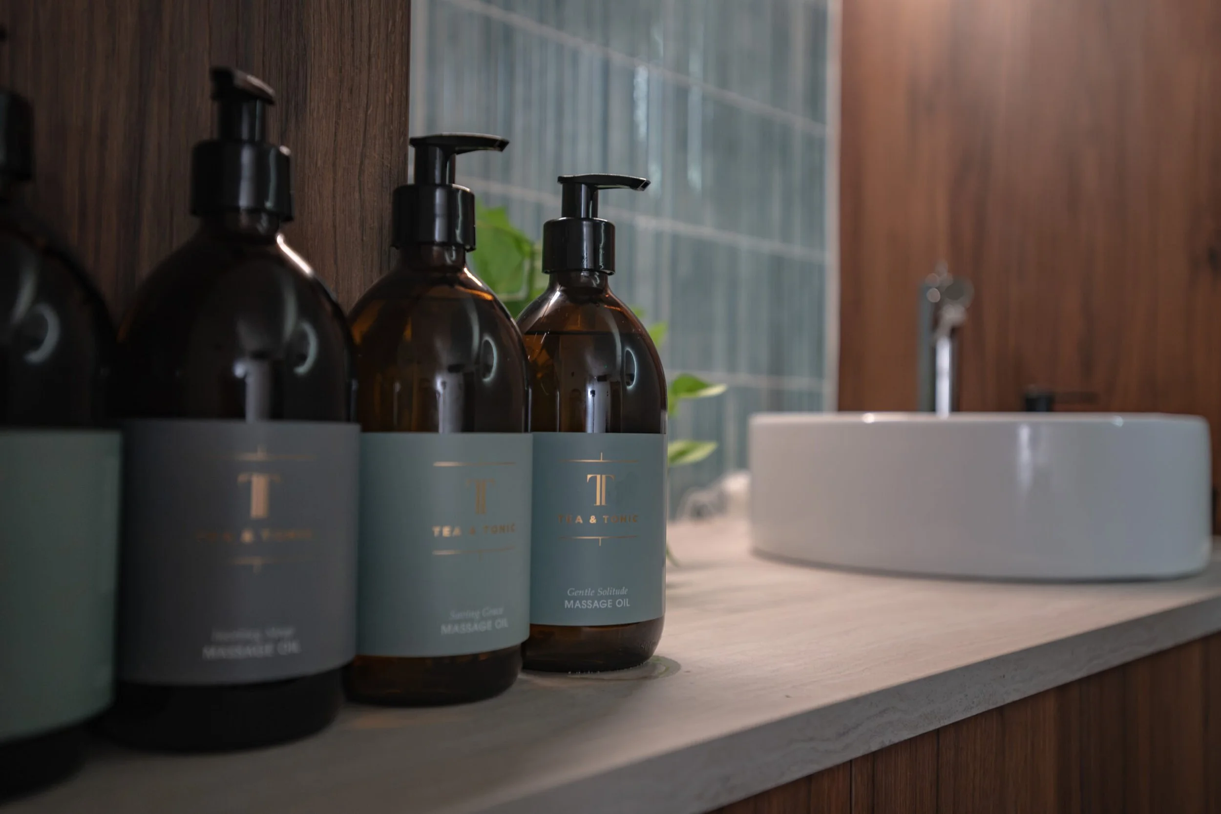 A collection of Tea & Tonic massage oil bottles displayed at Being Wellness Centre in St Albans, highlighting premium botanical products used during professional massage treatments.
