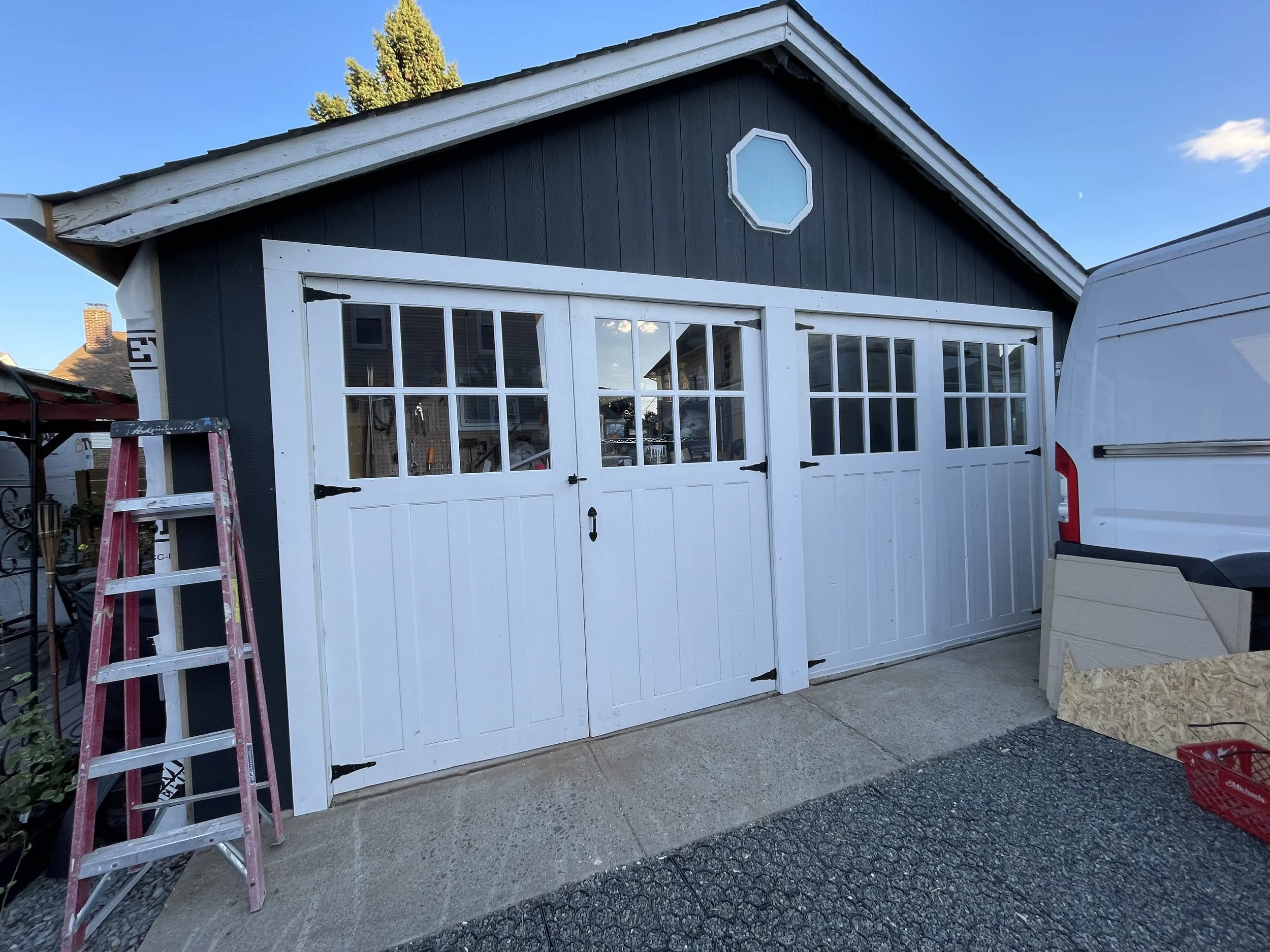 White double garage doors, carriage door style on a blue garage.