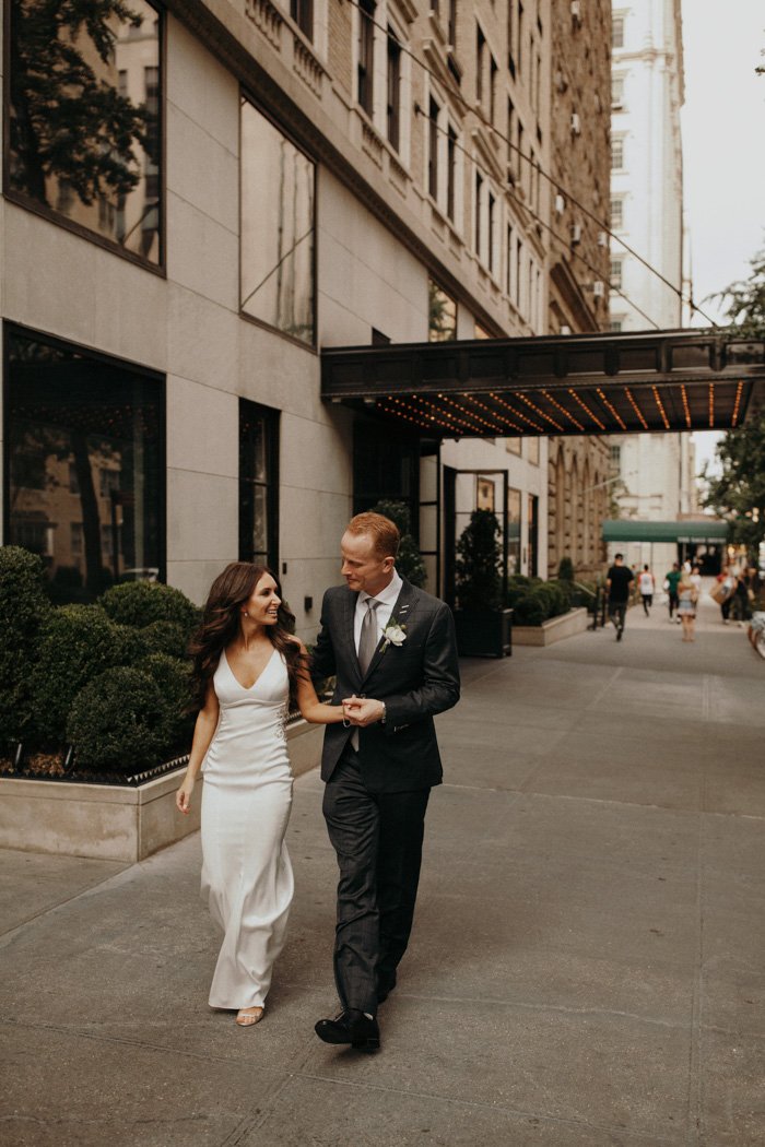 Bride and groom walking on city sidewalk