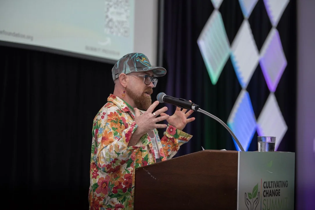 Dr. Leo Taylor speaking from a podium on transgender empowerment at the 2025 Cultivating Change Summit in Portland, Oregon.