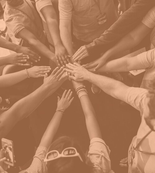 Un groupe de personnes joignant leurs mains au centre pour symboliser la coopération et l'unité.