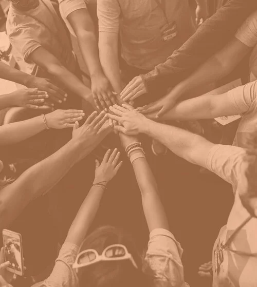 Un groupe de personnes joignant leurs mains au centre pour symboliser la coopération et l'unité.