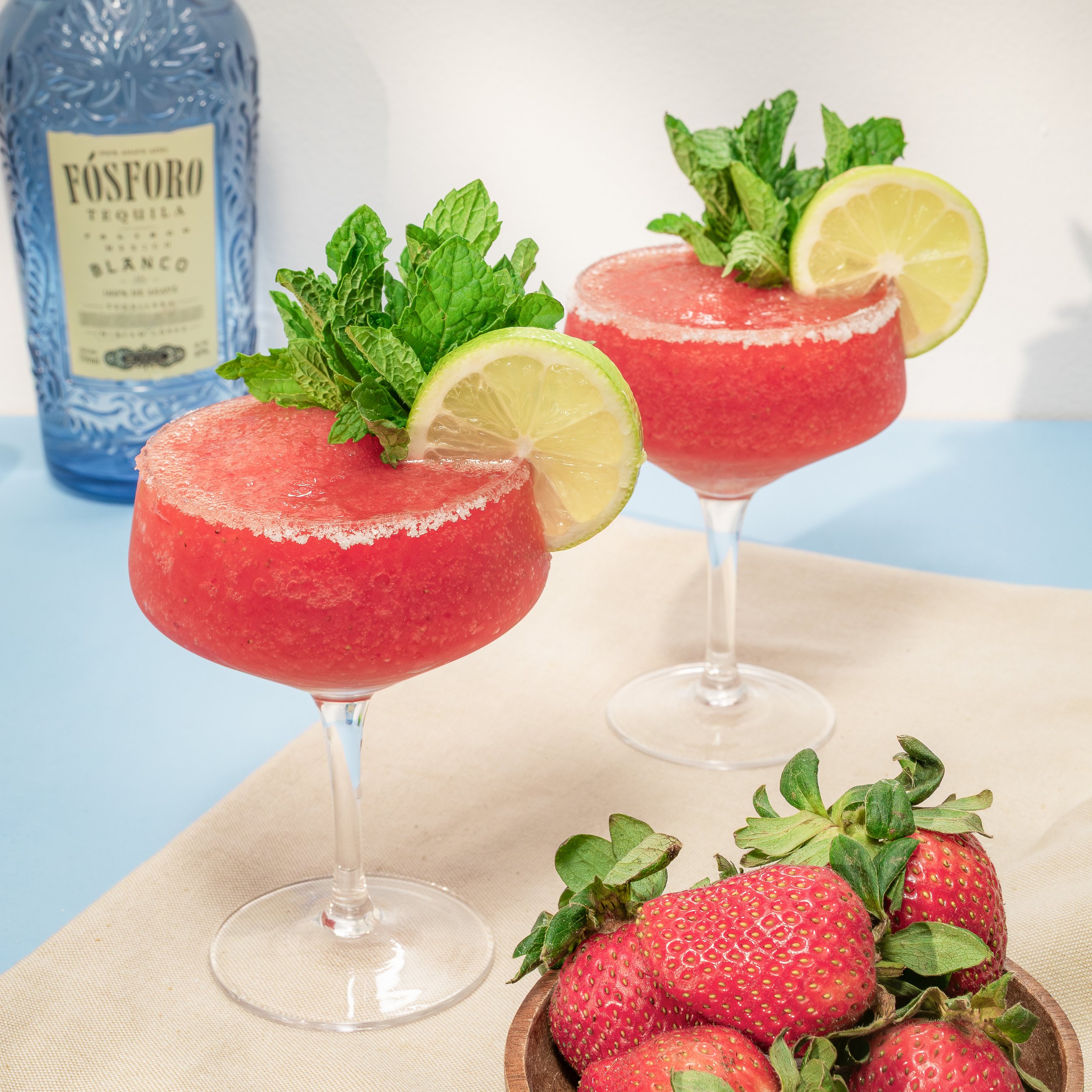 Frozen strawberry margarita with tequila, lime wheel, and fresh mint garnish in coupe glass