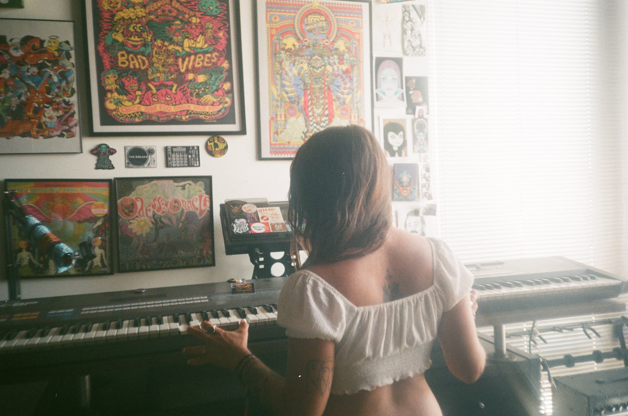 Person playing keyboard in room with colorful wall art and posters