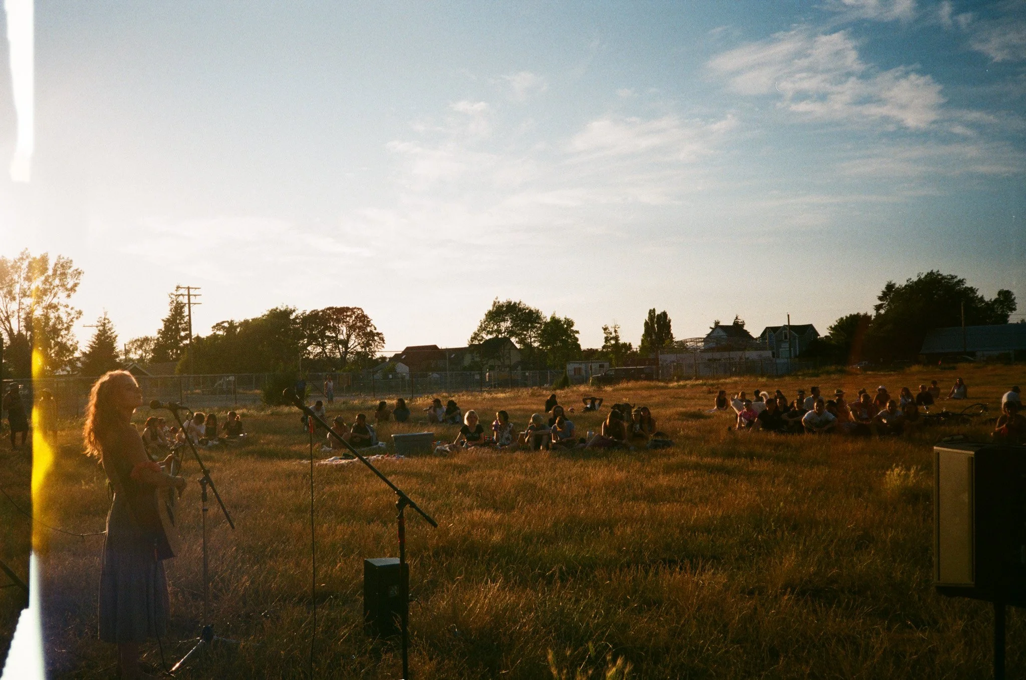 Outdoor music performance in field with audience at sunset