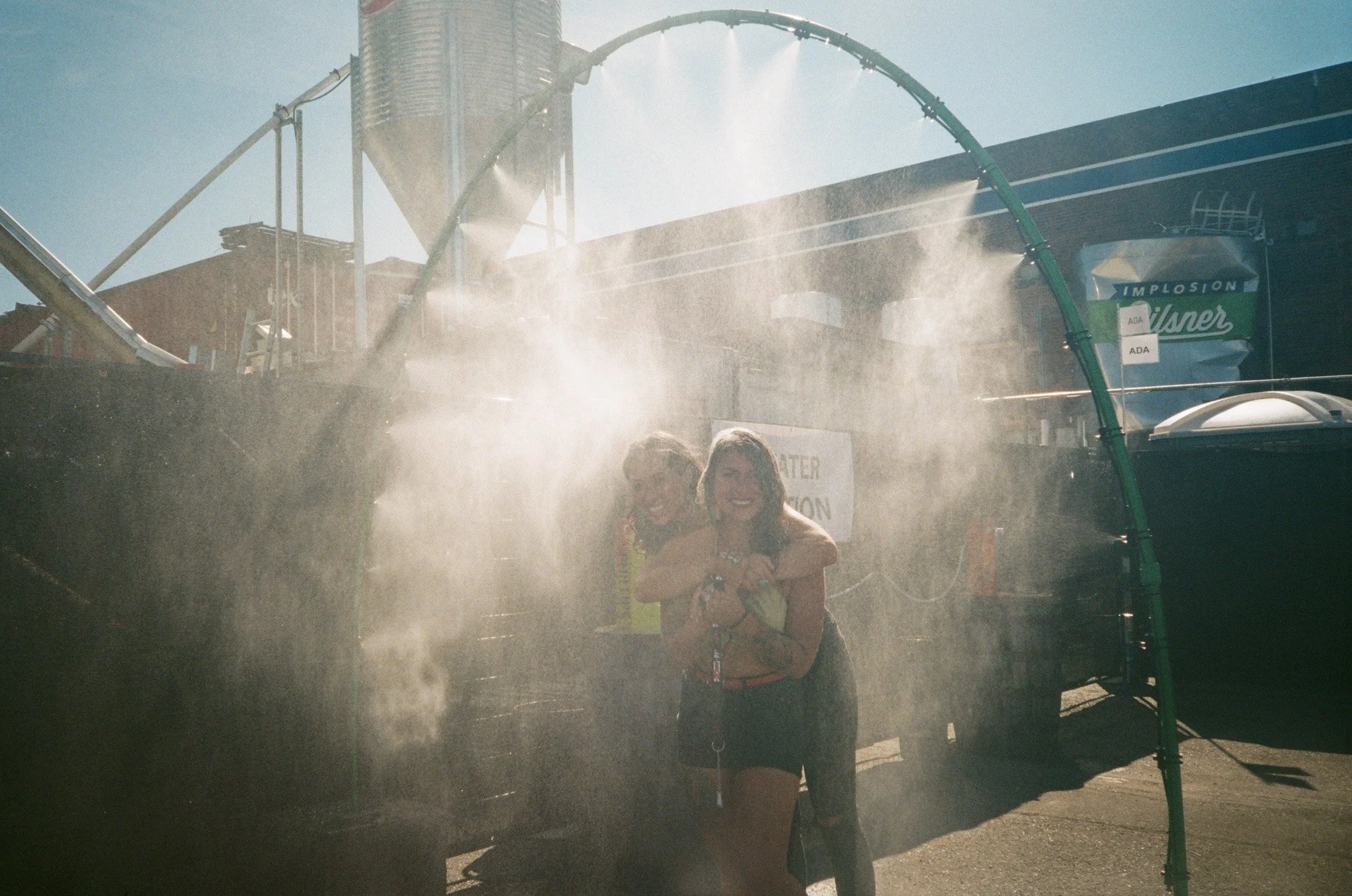 People enjoying a misting spray at an outdoor event.
