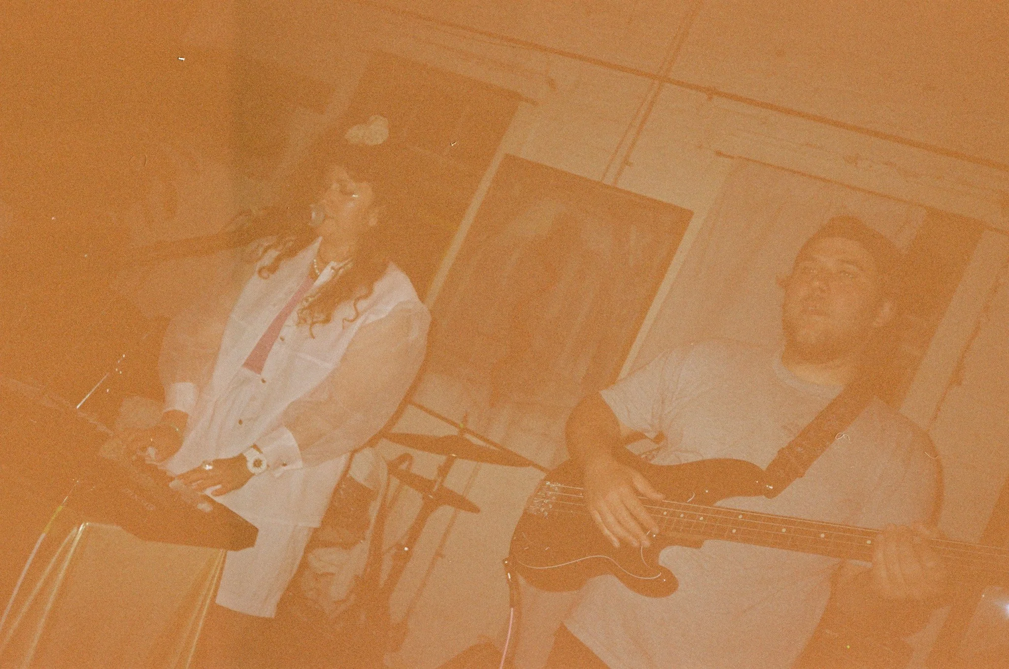 Musicians performing in a dimly lit venue, with a woman playing a keyboard and a man playing a guitar.
