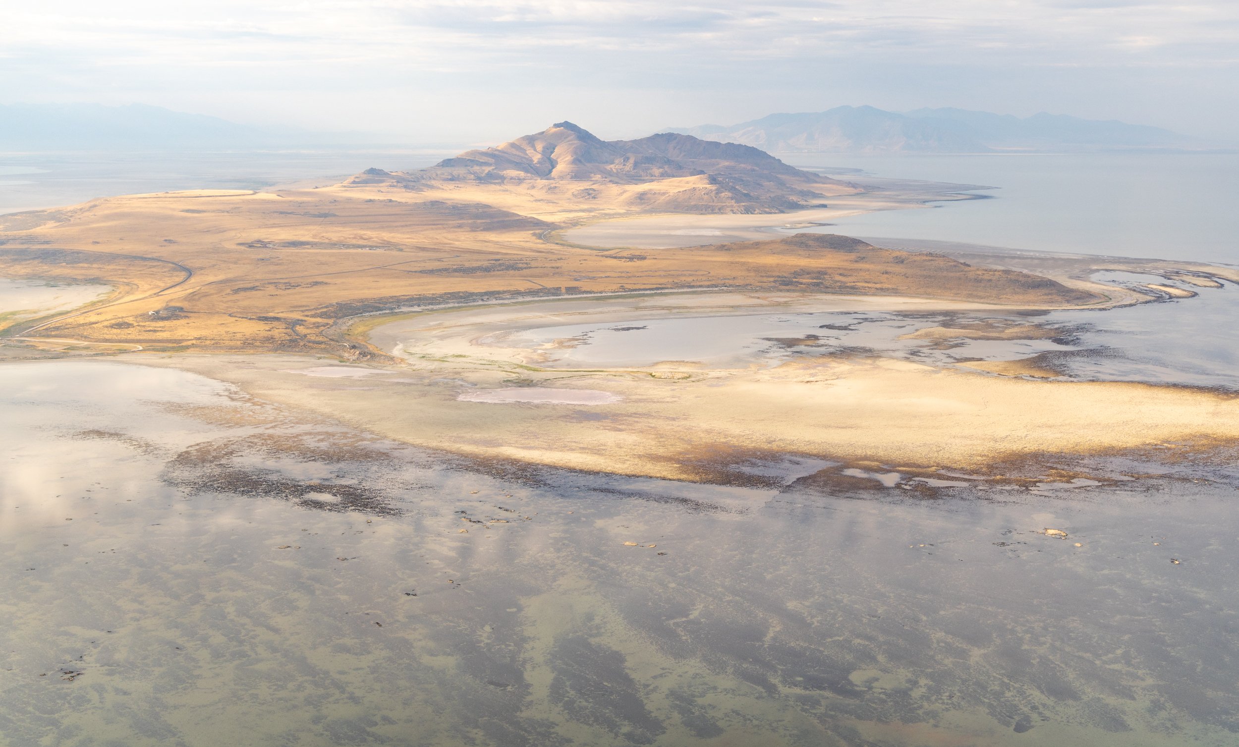  Aerial view of Antelope Island from the North.  Dry and bleached microbialites can be seen in front of the island, and submerged microbialites can be seen in shallow water in the foreground.  